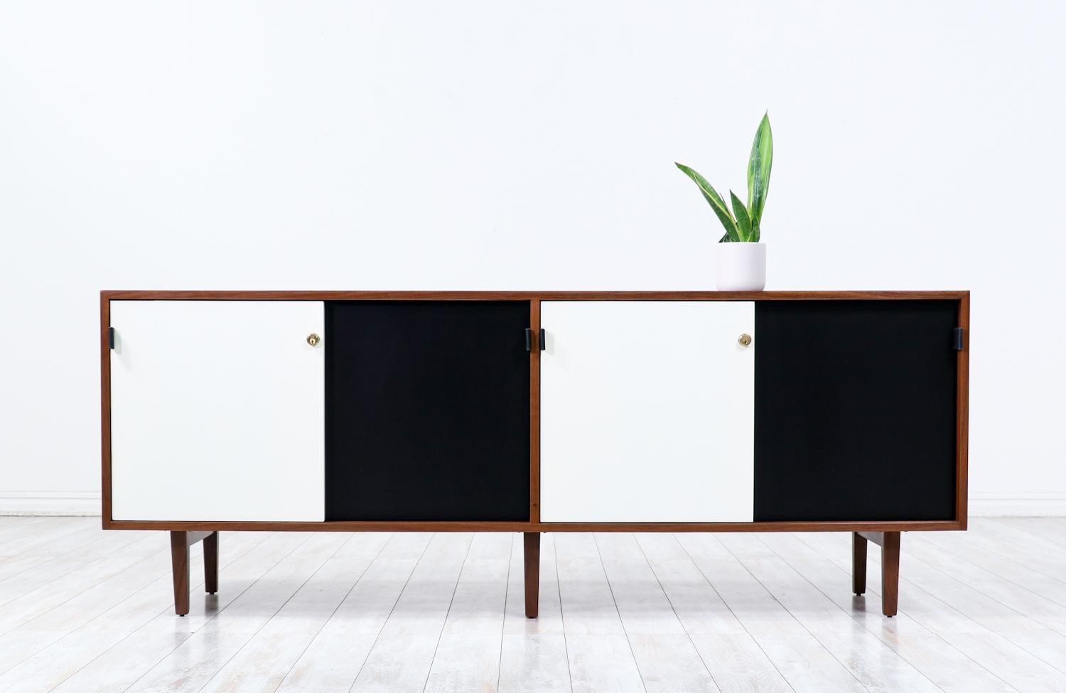 Élégante crédence conçue par l'architecte et designer Florence Knoll et fabriquée par Knoll Associates Inc, vers les années 1950. Ce design emblématique se caractérise par une caisse en bois de noyer reposant sur six pieds en noyer massif. Quatre