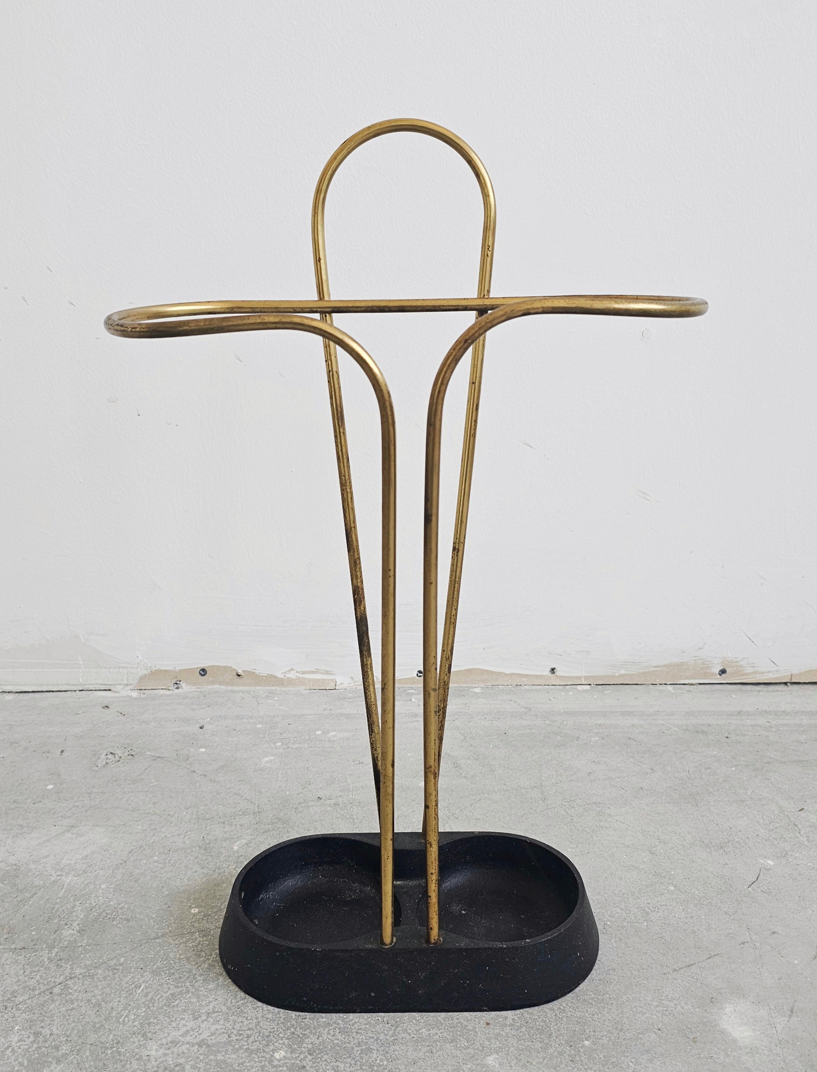 Vous trouverez dans cette annonce un très rare porte-parapluie en laiton et en fer peint en noir, attribué à Carl Aubock. Elle comporte une base en fer lestée conçue pour recueillir l'eau de pluie, avec un porte-parapluie en laiton au design