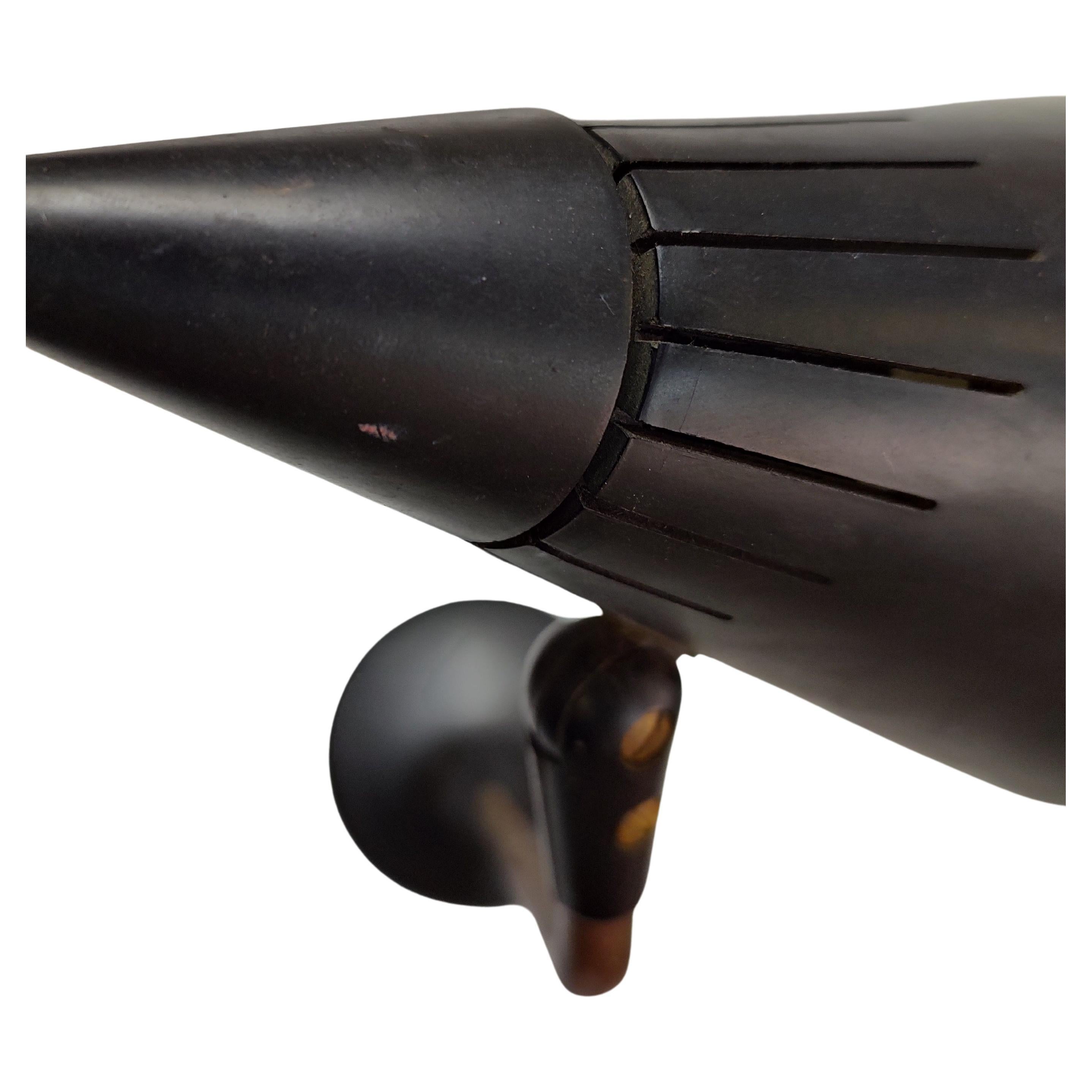Lampe de bureau simple et élégante en forme de cône avec un axe en cuivre et un abat-jour et une base noirs. Au sommet du cône se trouve l'interrupteur de lumière, une caractéristique unique. Une grille protège l'ampoule et l'utilisateur. En