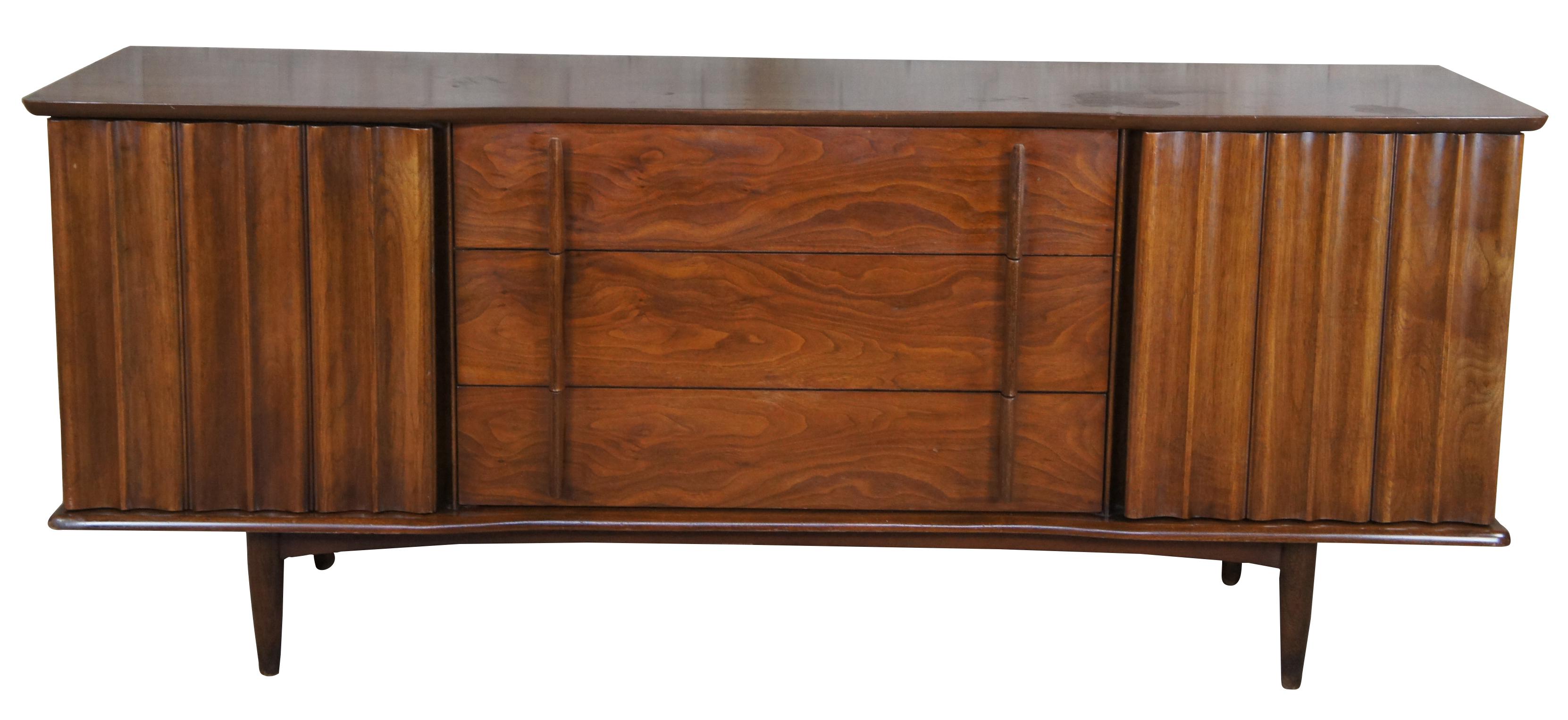 An exceptional Mid-Century Modern dresser & mirror or console by United Furniture Corporation, circa 1961. Made from walnut with a sculptural front that conceals 6 drawers and mirror. Each drawer is dovetailed and made from solid oak. The dresser is