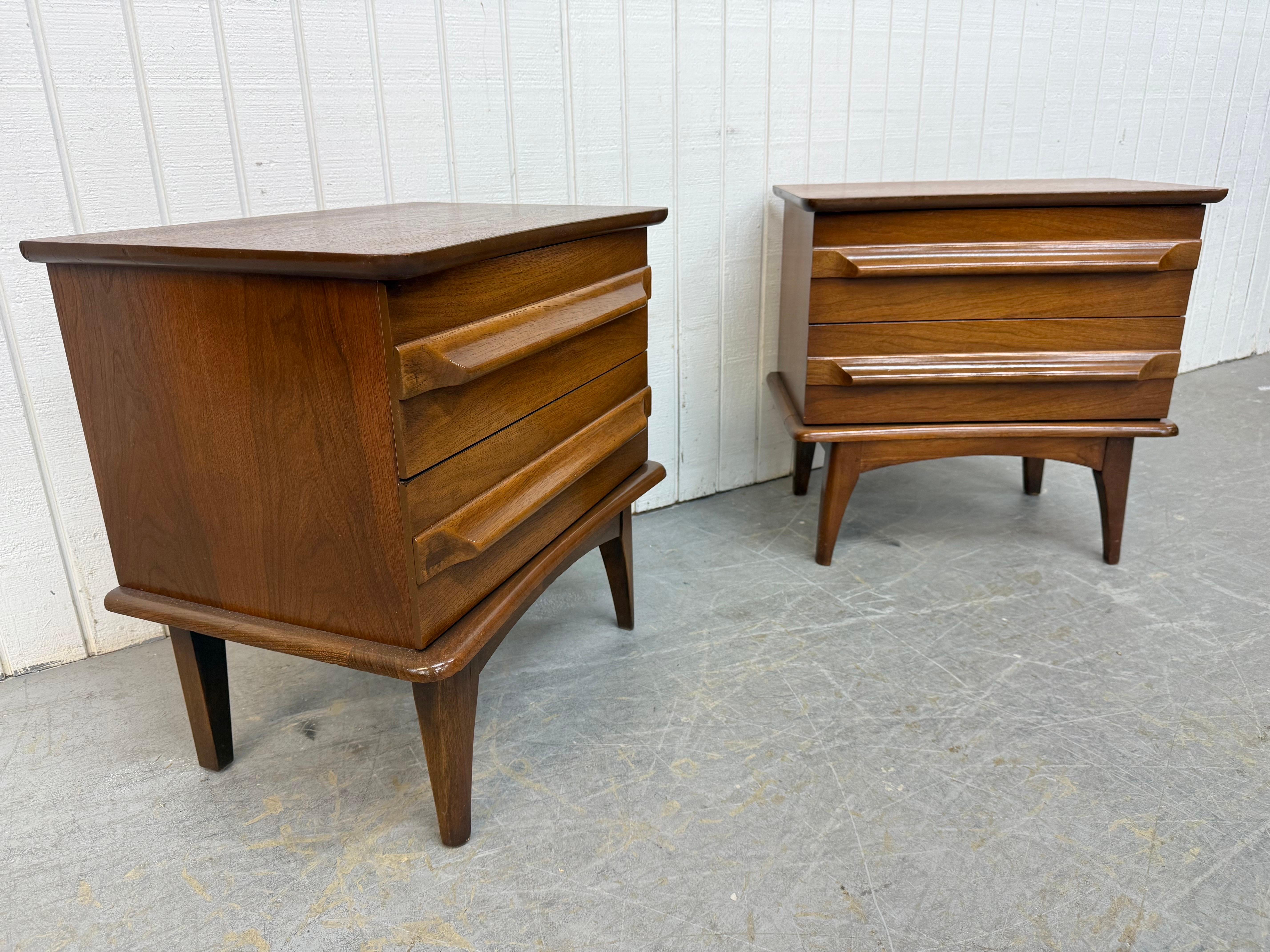 Estas mesillas de noche de nogal United de mediados de siglo ofrecen una sorprendente mezcla de detalles escultóricos y artesanía atemporal. Con atrevidos perfiles frontales en ángulo y tiradores de cajón profundamente tallados, encarnan el icónico