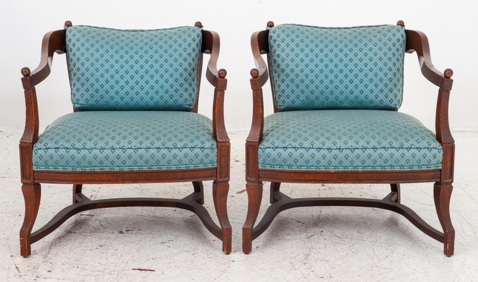 Mid-Century Modern pair of walnut lounge armchairs with caned backrest raised on cabriole legs joined by stretchers, seat and cushion in blue upholstery.

Dimensions: Each: 29