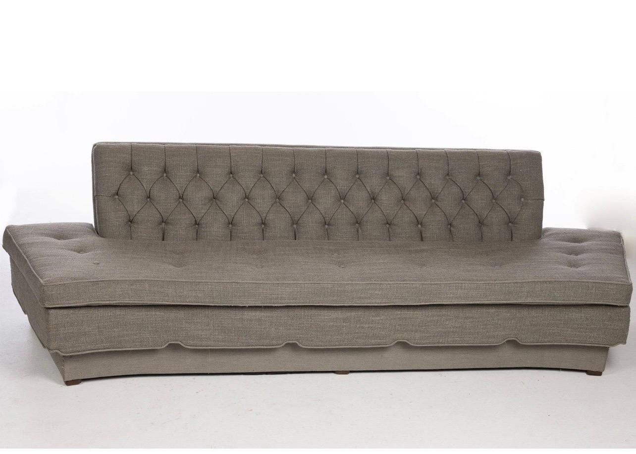 Mid-Century Upholstered Sofa, the button tufted rectangular back above a loose cushioned seat with canted sides above a conforming plinth. The sofa has been previously re-upholstered in a Holly Hunt fabric. 