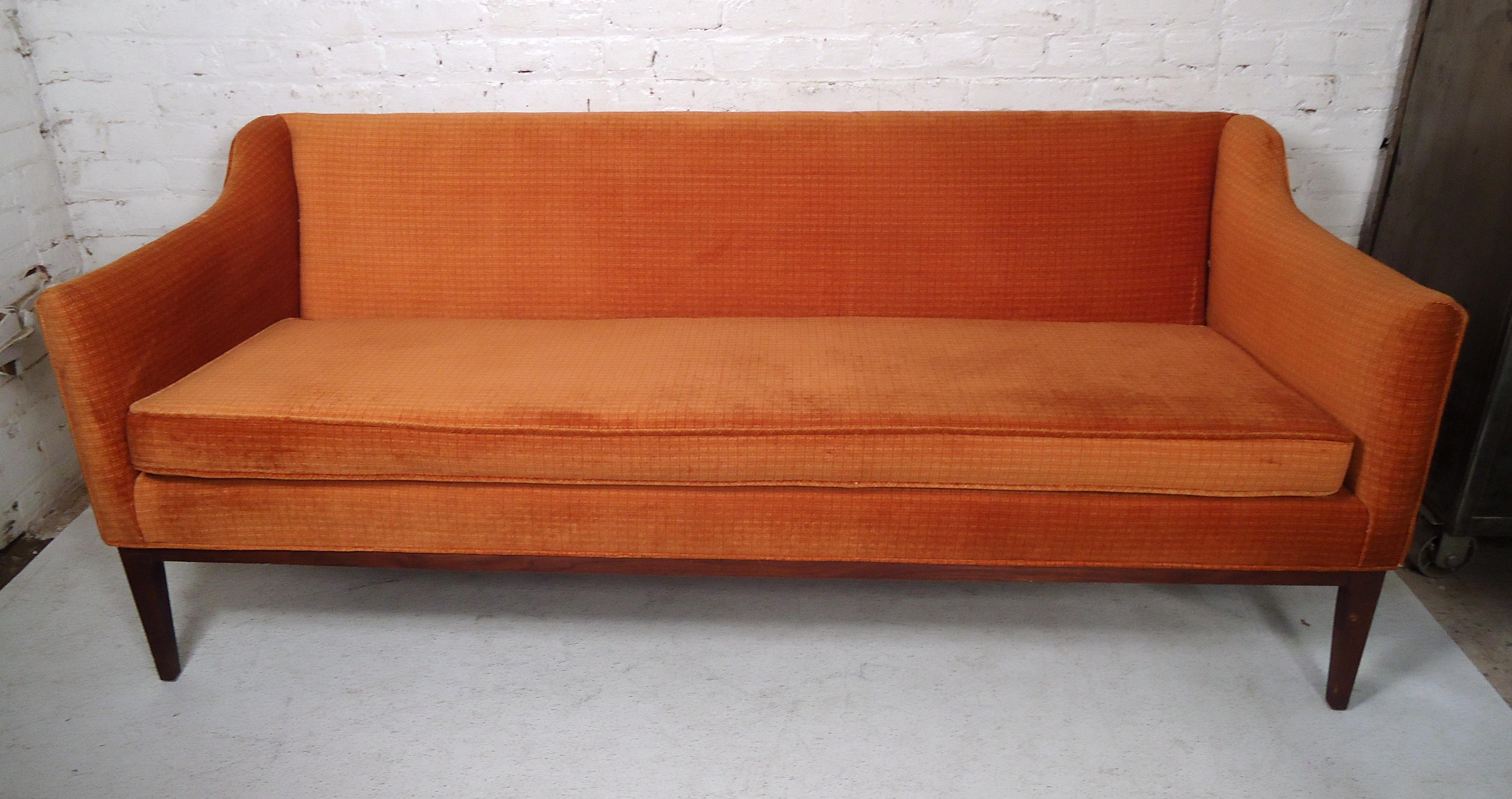 This sleek vintage modern couch features an orange upholstered body with sturdy hand-sculpted legs.
This sofa would make a great addition to any home or office.

Please confirm item location (NY or NJ).