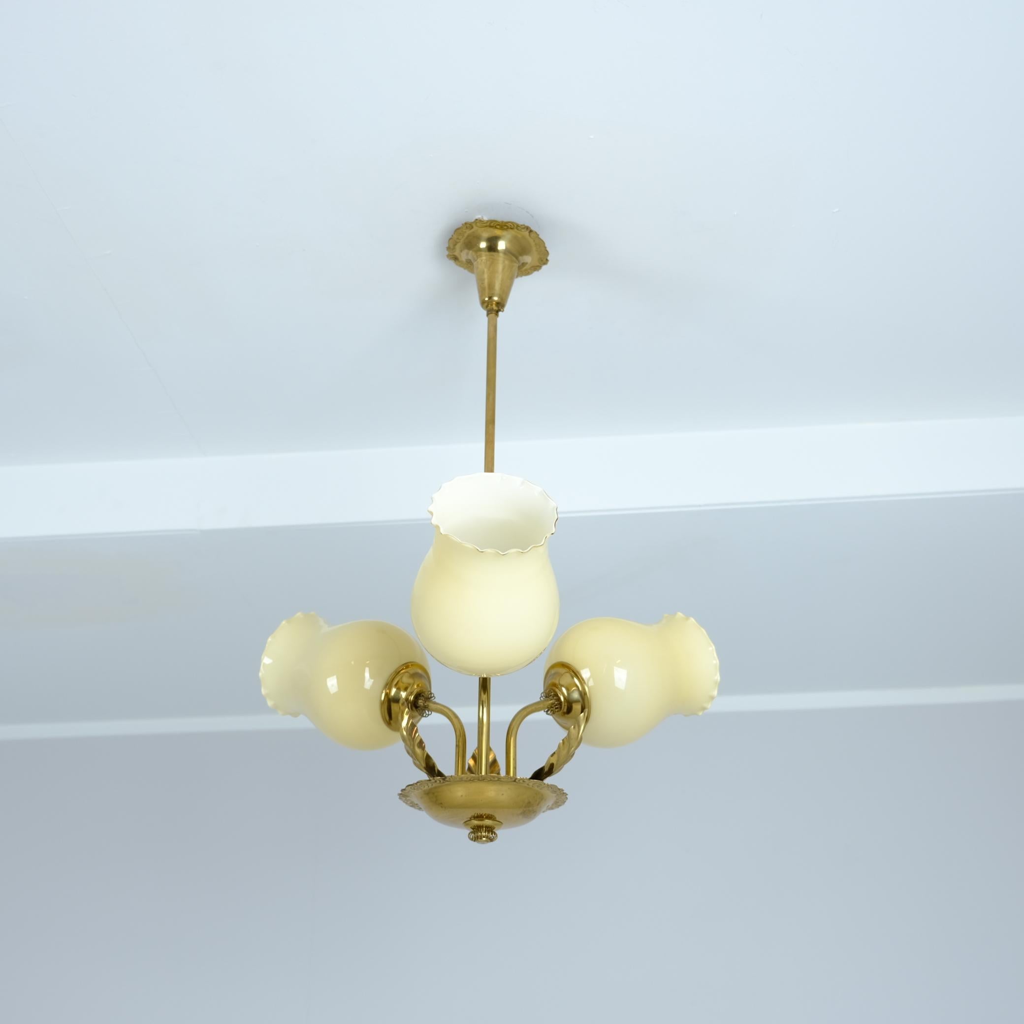 Una bellissima e delicata lampada da soffitto finlandese di metà secolo di Sario, risalente agli anni '50, che era un produttore di illuminazione di metà secolo in Finlandia. La lampada presenta tre basi con paralumi in vetro opalino e una forma