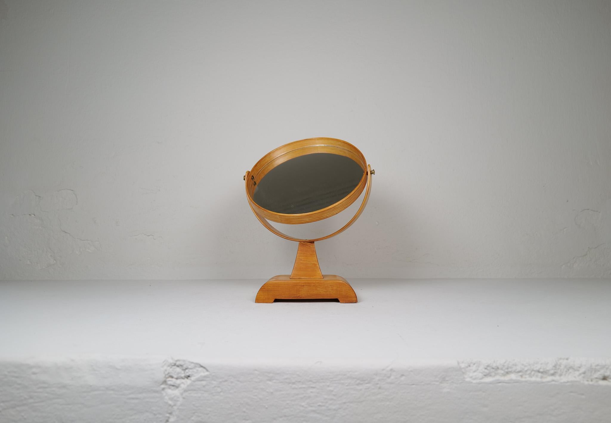 This midcentury table mirror in solid pine was produced in Sweden during the 1970s. 
The grain of the wood in the rounded parts of the mirror is wonderful and the bade with its patina gives a great character to this unusual mirror. The mirror can be