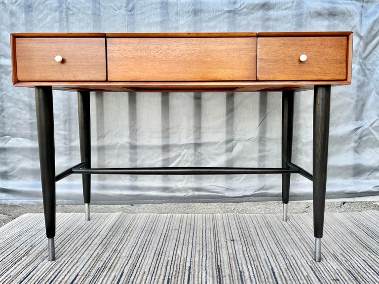 Vintage Mid-Century Modern vanity/ writing desk by Raymond Loewy for Mengel Furniture. Circa 1950s. 
Features a mid century modern sleek design with a light wood case, a hidden compartment with a mirror, and two side drawers. raised on black wood