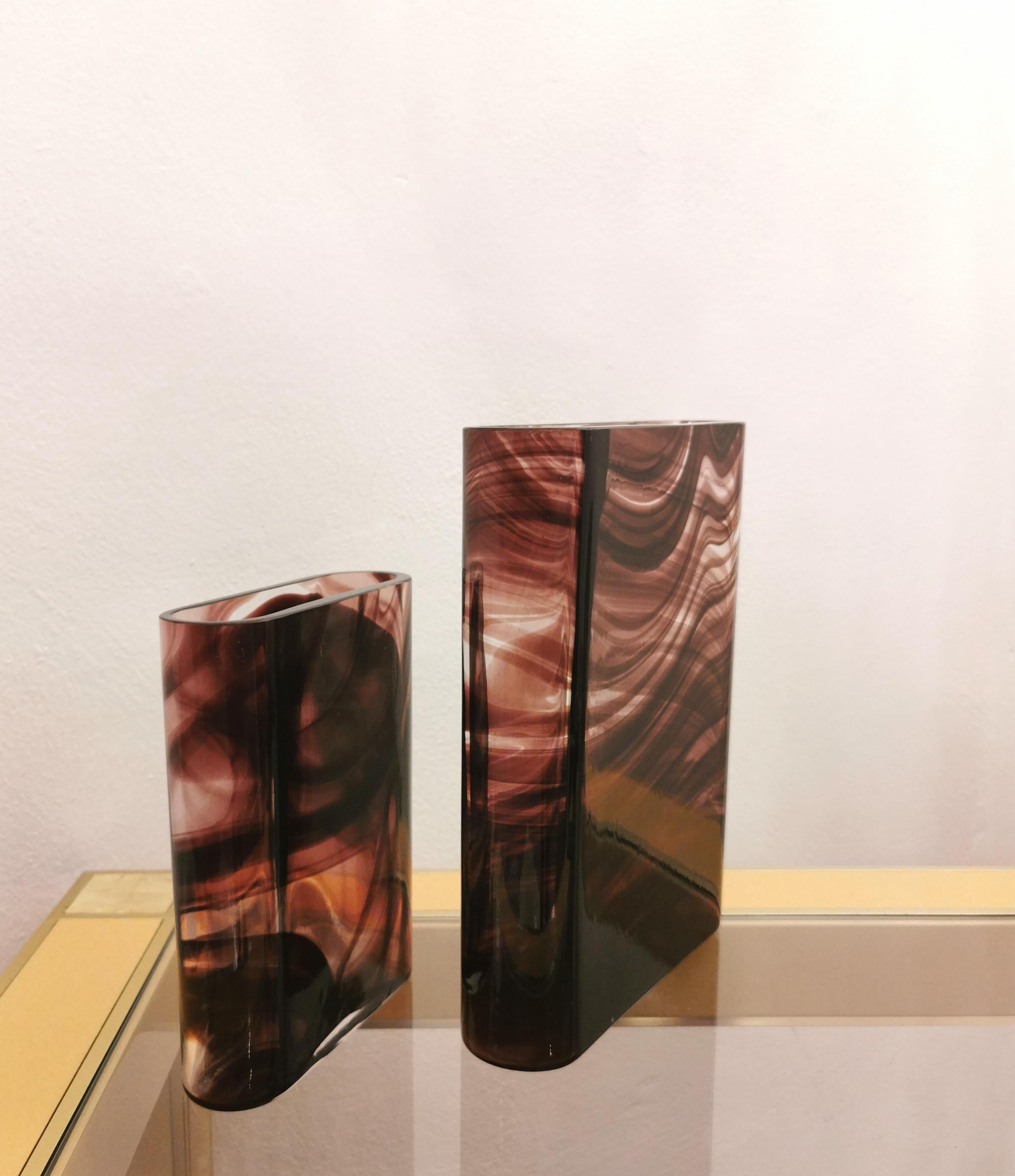 Set of 2 vases produced in Murano by the Maestri Muranesi company in the 70s. The pair is in transparent Murano glass and with faux maroon-colored decorations. Oval body with flush mouth.