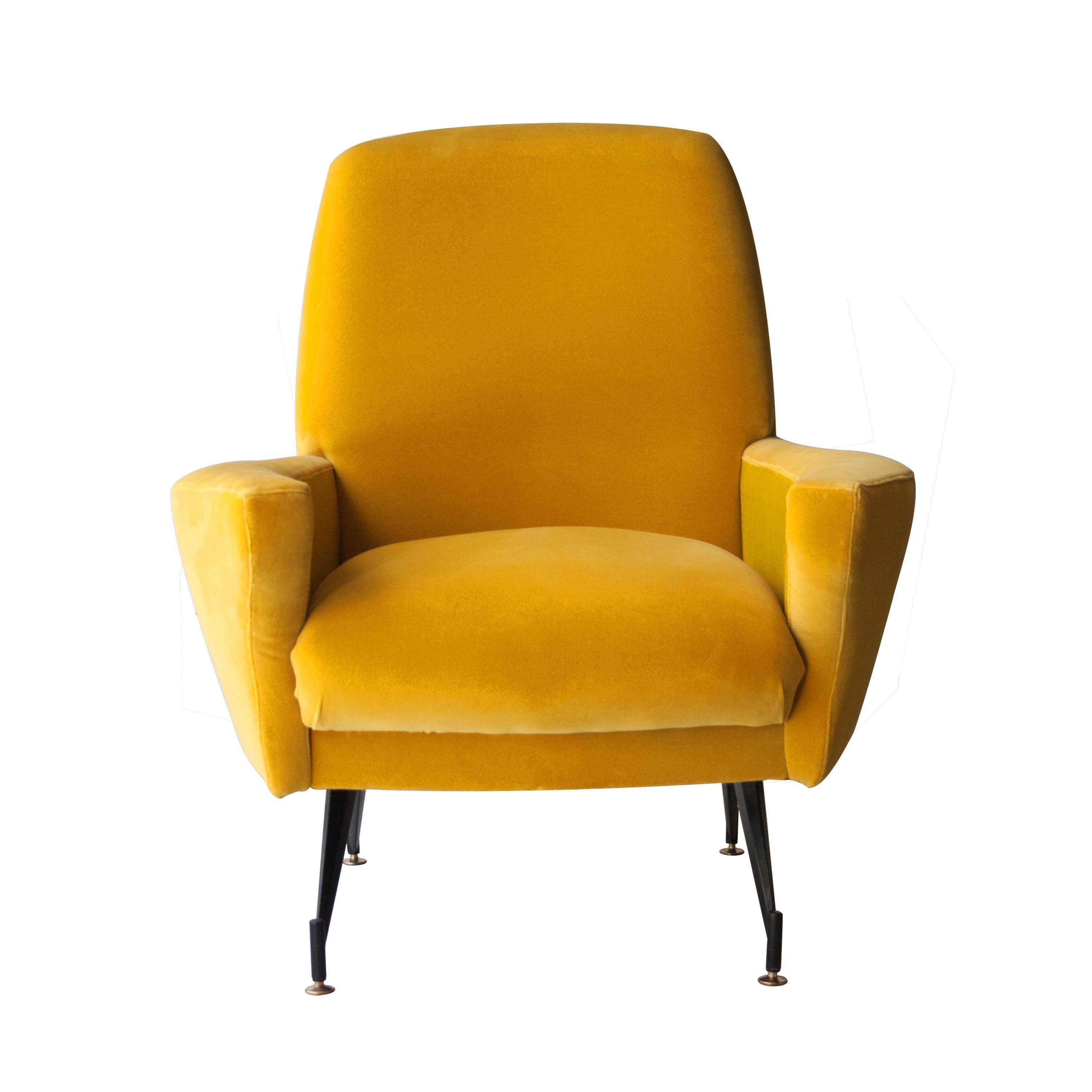 Pair of midcentury Italian armchairs made of solid wood structure with mustard yellow velvet upholstery, and black lacquered iron legs, finished with brass detail.