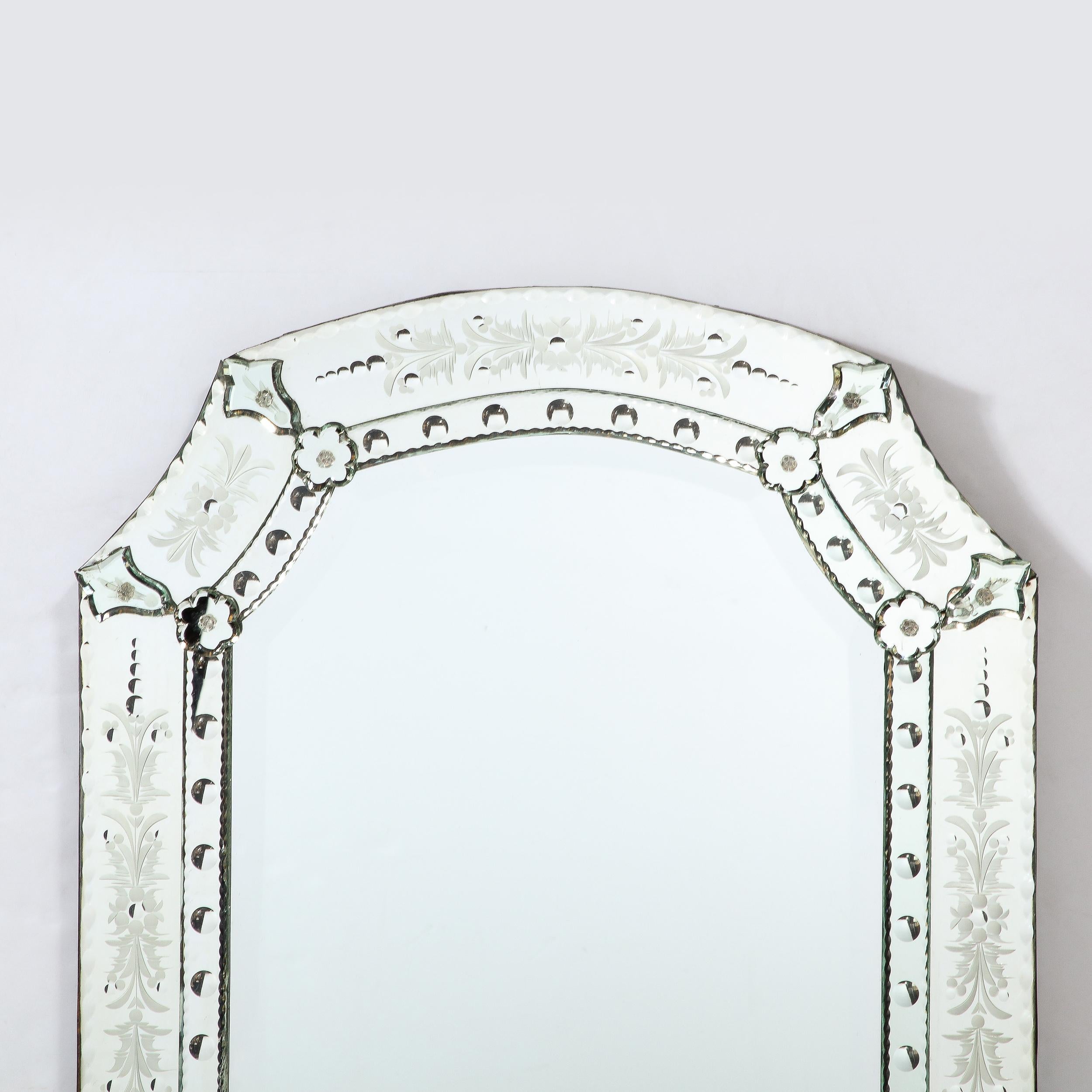 This beautiful Mid-Century Modern Venetian glass mirror was executed in Italy, circa 1960. It features a rectangular body with an arch form top- consisting of two curved panels on its neck and a demilune panel crowning the form. The mirrored