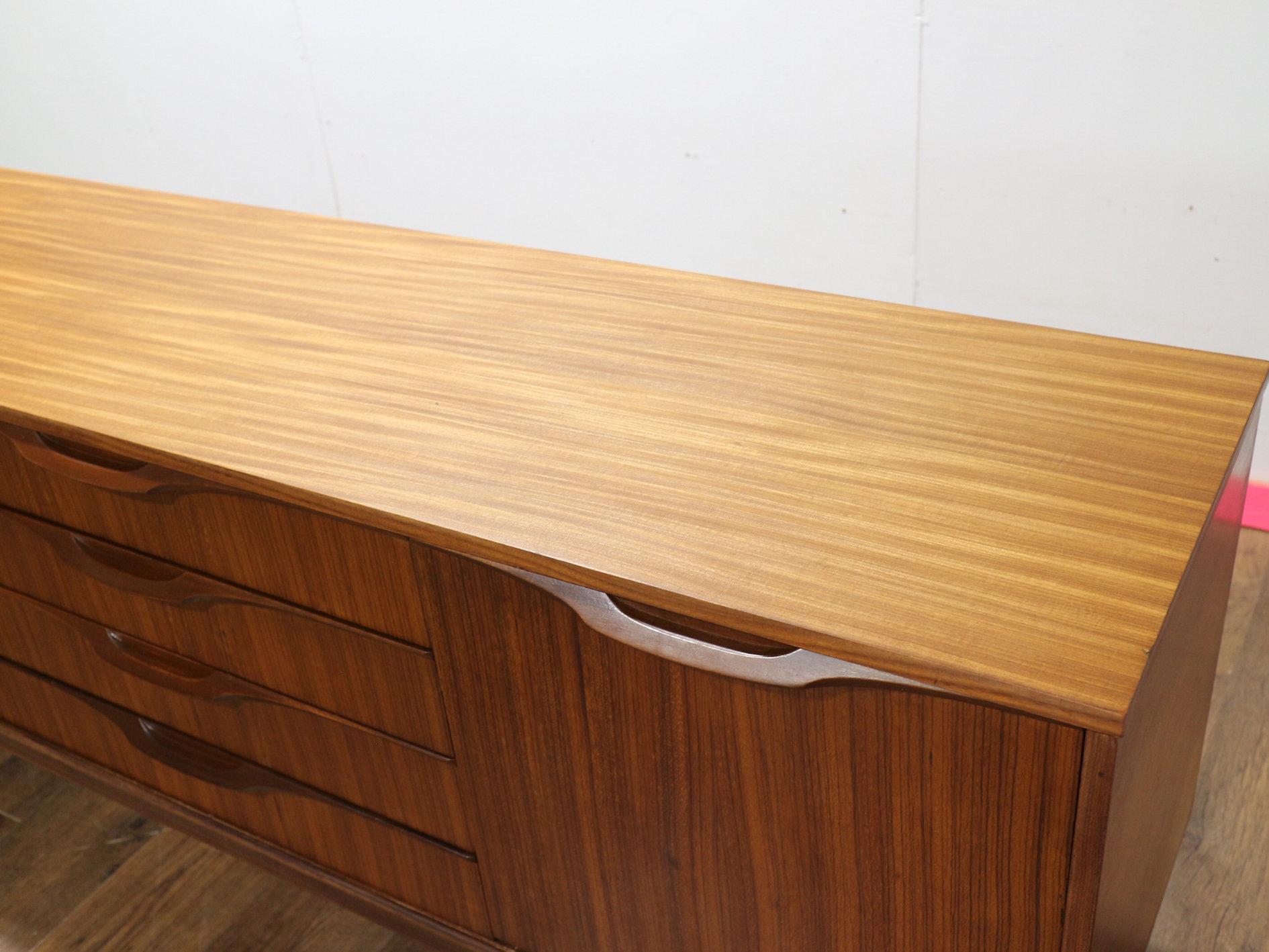 A stunning credenza sideboard by British furniture maker Elliots of Newbury. Made from afromosia teak, this mid-century modern vintage piece boasts impeccable craftsmanship and timeless elegance. Great storage is efficiently provided to keep your