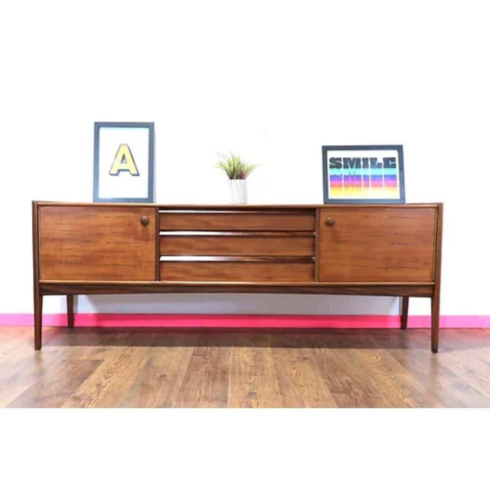 Mid Century Modern Vintage Afromosia Sideboard Credenza by Younger is a beautiful and rare find for any mid-century furniture enthusiast. Designed by John Herbert for A.Younger Ltd, this stunning teak and afrormosia wood sideboard is a true