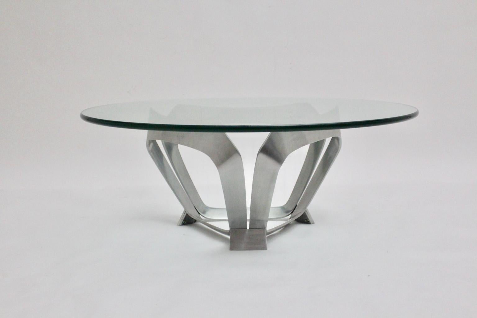 This presented Mid-Century Modern vintage coffee table was designed by Knut Hesterberg 1960s for Ronald Schmitt Germany. The coffee table shows an aluminum base in triangle shape with a clear glass plate with a thickness of 2 cm and polished