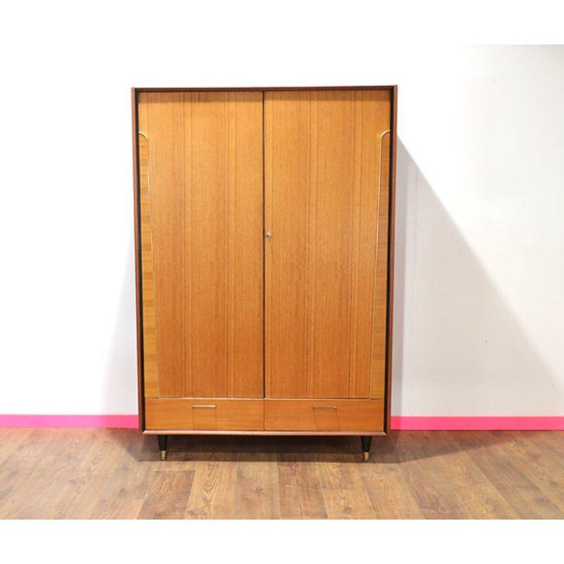 A stunning mid century armoire by British furniture maker, Beautility. 

This fabulous armoire offers great storage whilst looking fantastic, with both a hanging section as well  a lower drawer in this wardrobe. The torpedo legs really make this