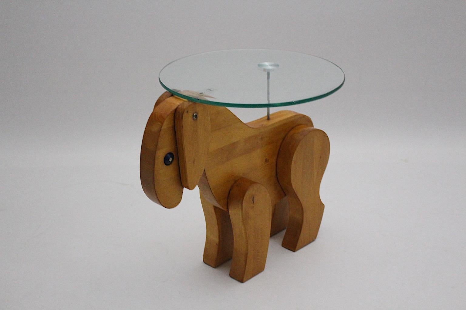 Mid-Century Modern vintage side table or coffee table from oiled ash and tempered glass plate, which was designed and made 1970s Austria.
The base shows an amazing base formed like a sheep from ash wood and cords, while the clear facetted glass