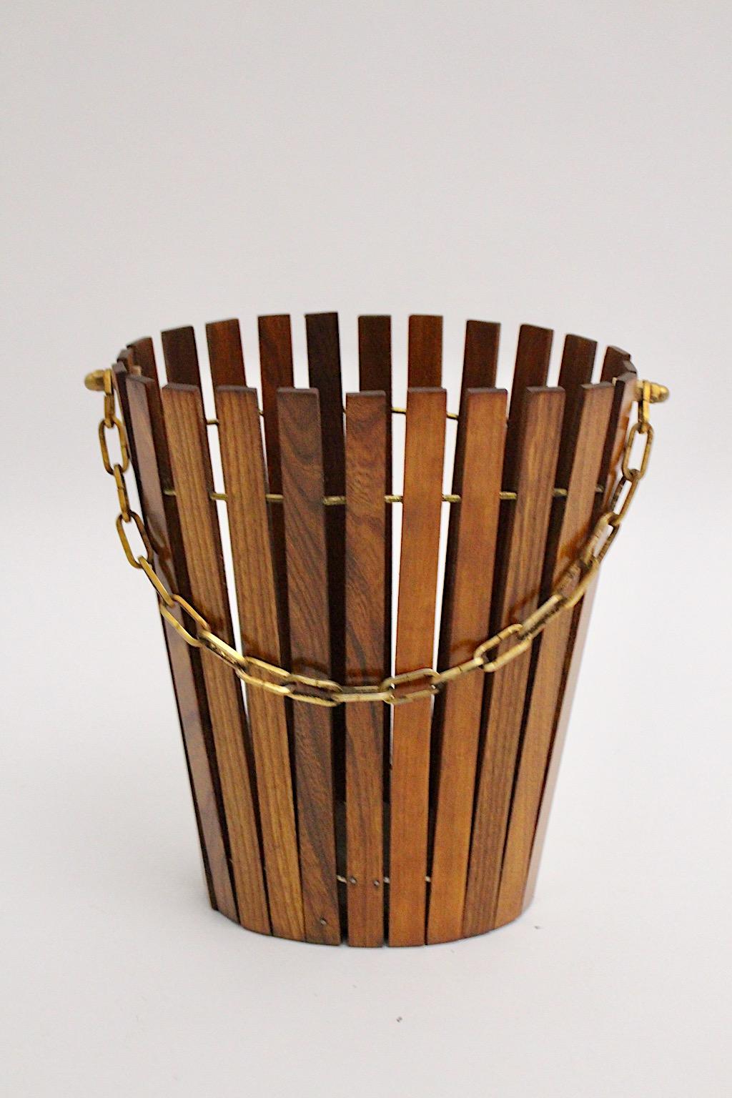 Mid-Century Modern vintage paper basket from ash and brass Austria 1960s.
The conical oval shape is formed with brown stained and lacquered ash lamellas and based with a pressboard plate.
While the slats are connected with brass rings the basket