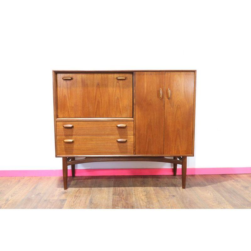 A scarcely seen Mid Century teak drinks cabinet manufactured by G-Plan.
A beautifully proportioned piece constructed from teak with contrasting solid afromosia detailing.
Features two drawers, a drop down bar and large shelved cupboard to the right
