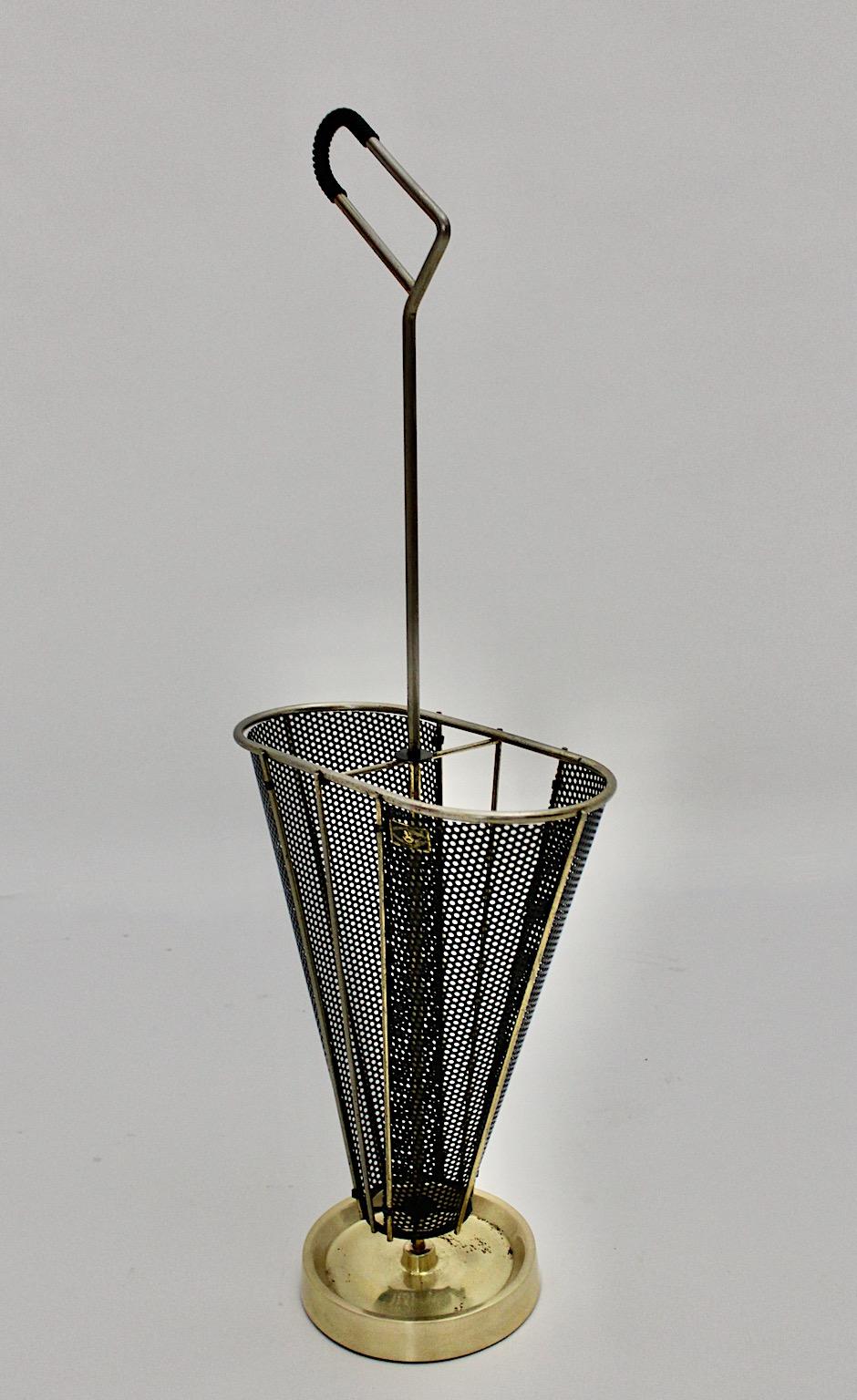 Mid-Century Modern vintage umbrella stand from black lacquered metal, brass and plastic, 1950s Germany.
A stunning umbrella stand in black and golden color tones from 1950s designed and manufactured in Germany.
While the conical shaped body shows