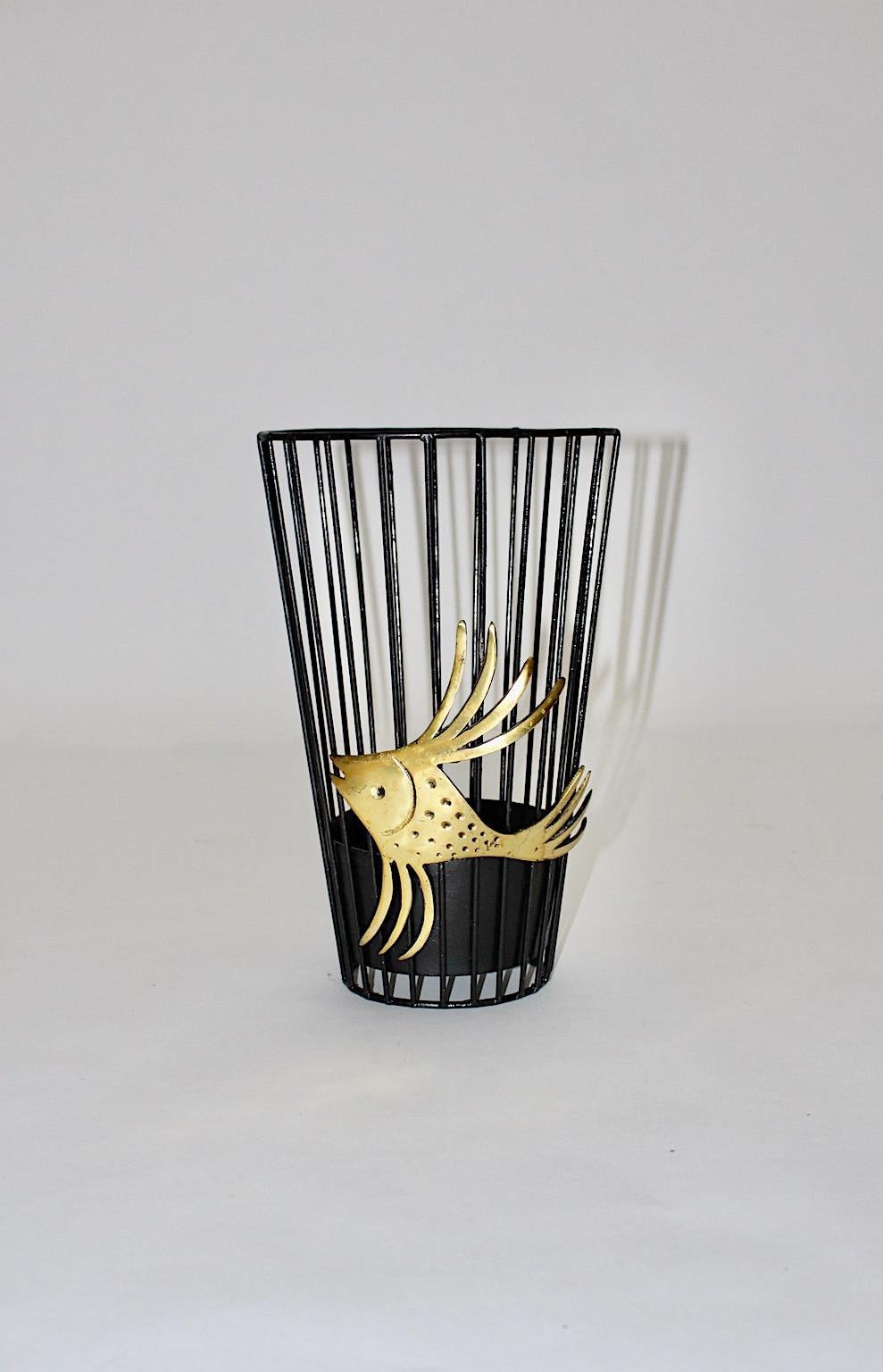 Mid Century Modern vintage umbrella stand or paper basket from metal and brass by Walter Bosse 1950s Austria.
Stunning fish like brass detail performs the umbrella stand for a charming basket for many umbrellas. Through a cast iron tray it provides