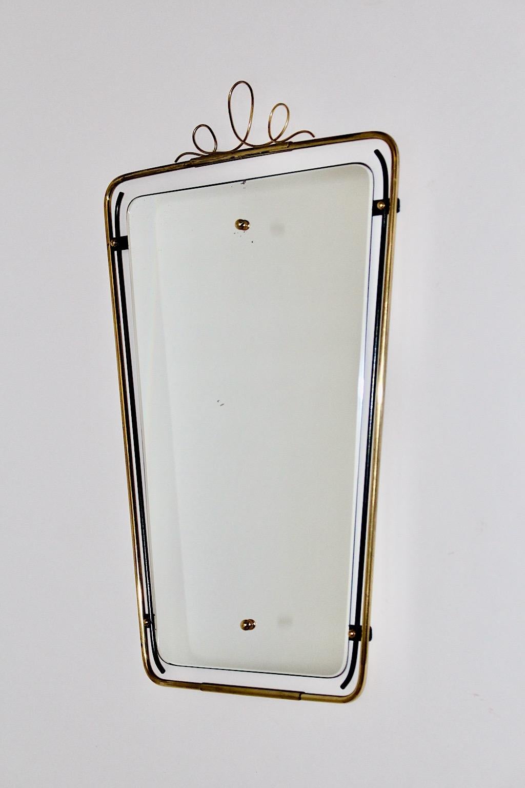 Mid Century Modern vintage wall mirror in rectangular form from brass and black metal wire 1950s Italy.
Decorated with brass bullets on each side and cute loops on the upper part the rectangular wall mirror provides a dose of easygoing chic for