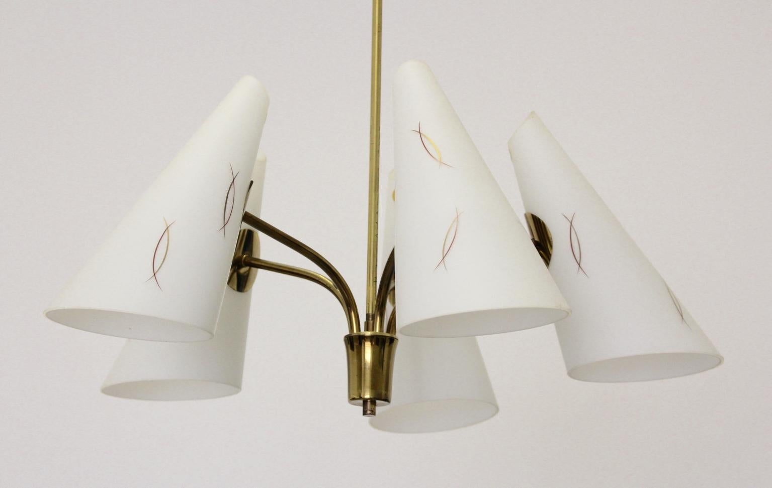 This Mid-Century Modern vintage brass chandelier with 5 patterned cone milk glass shades was designed and made by Rupert Nikoll, 1950s Vienna.
The chandelier is labeled.
Also the brass chandelier shows 5 E 27 sockets.
The chandelier is in very
