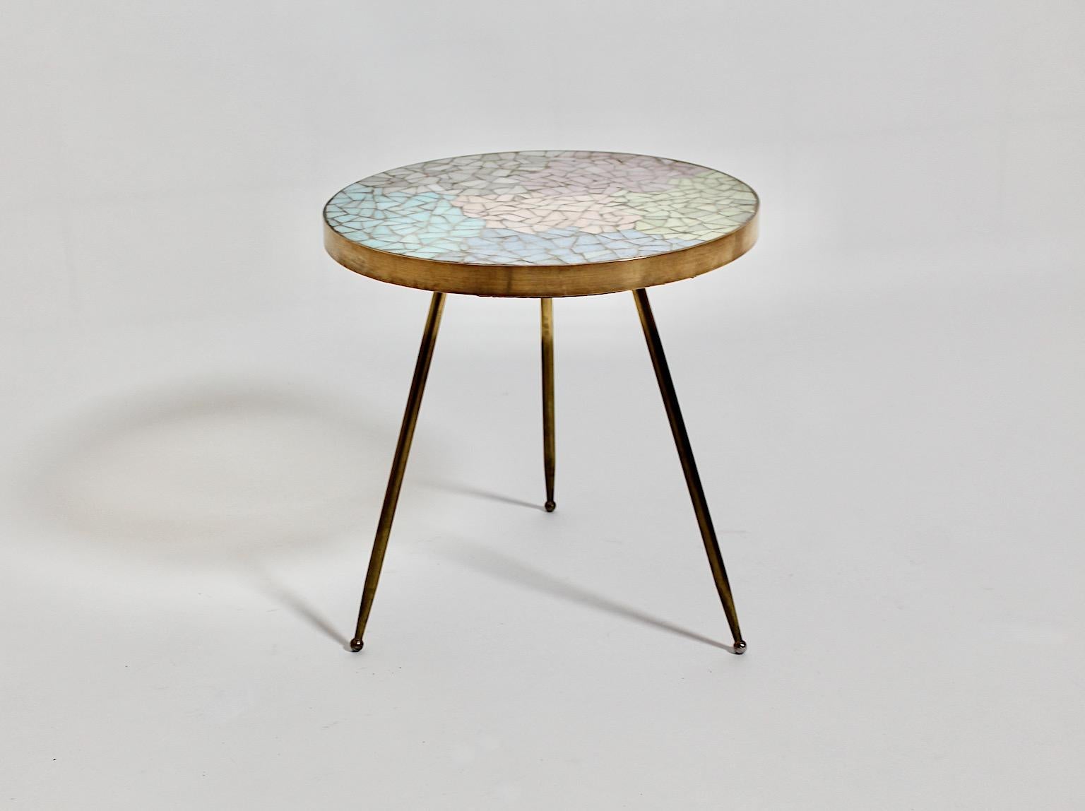 Mid Century Modern vintage circular small side table or flower table from brass and pastel colored mosaic elements 1950s Italy.
An amazing side table with brass base with three legs and a brass trim framed the top showing a pastel colored mosaic