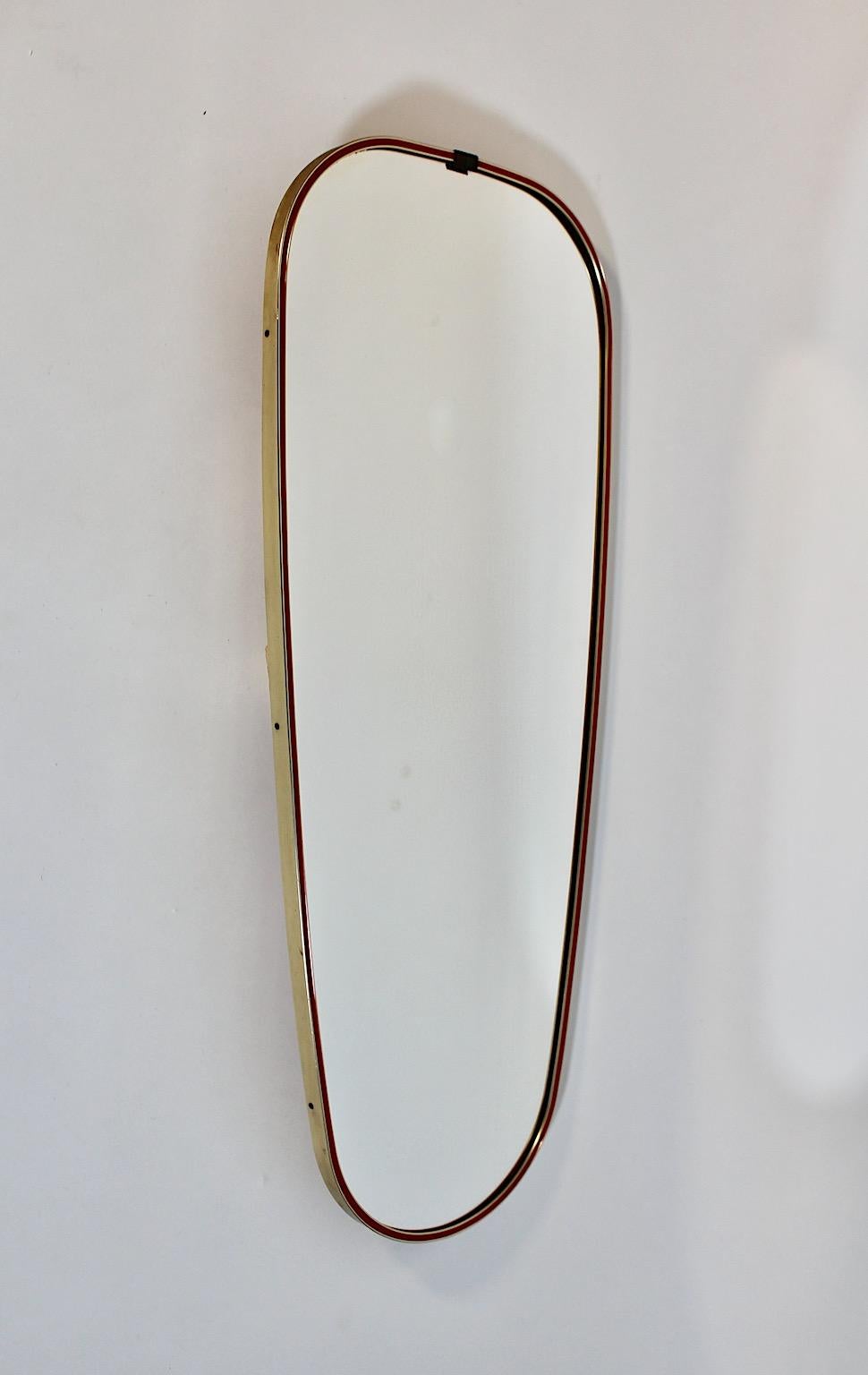 Specchio ovale vintage da terra o specchio a figura intera in ottone e plastica rossa, anni '50, Italia.
Uno splendido specchio da terra o a figura intera incorniciato in ottone e non rivestito con finiture in plastica rossa.
La cornice, larga 9 mm,
