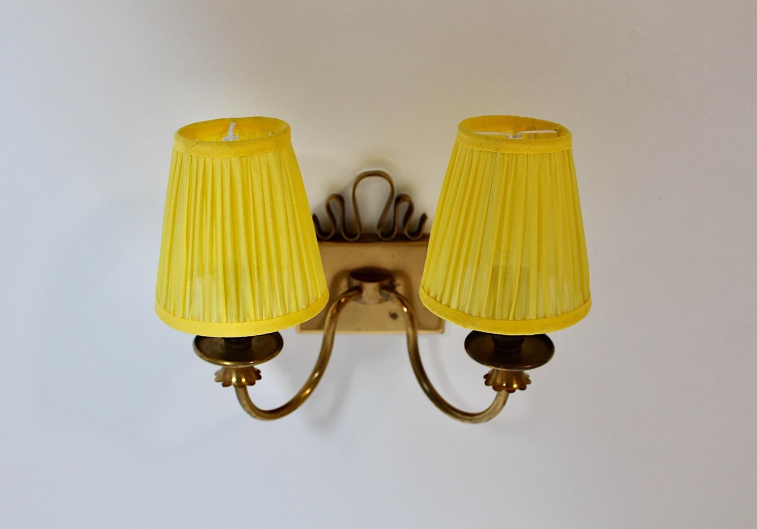 Mid-Century Modern vintage brass sconce or wall light with new sunny yellow pleated lamp shades, 1950s Italy.
A charming sconce or wall light from solid brass with cute loops and an amazing decor at the arms.
This wall light shows two E 14