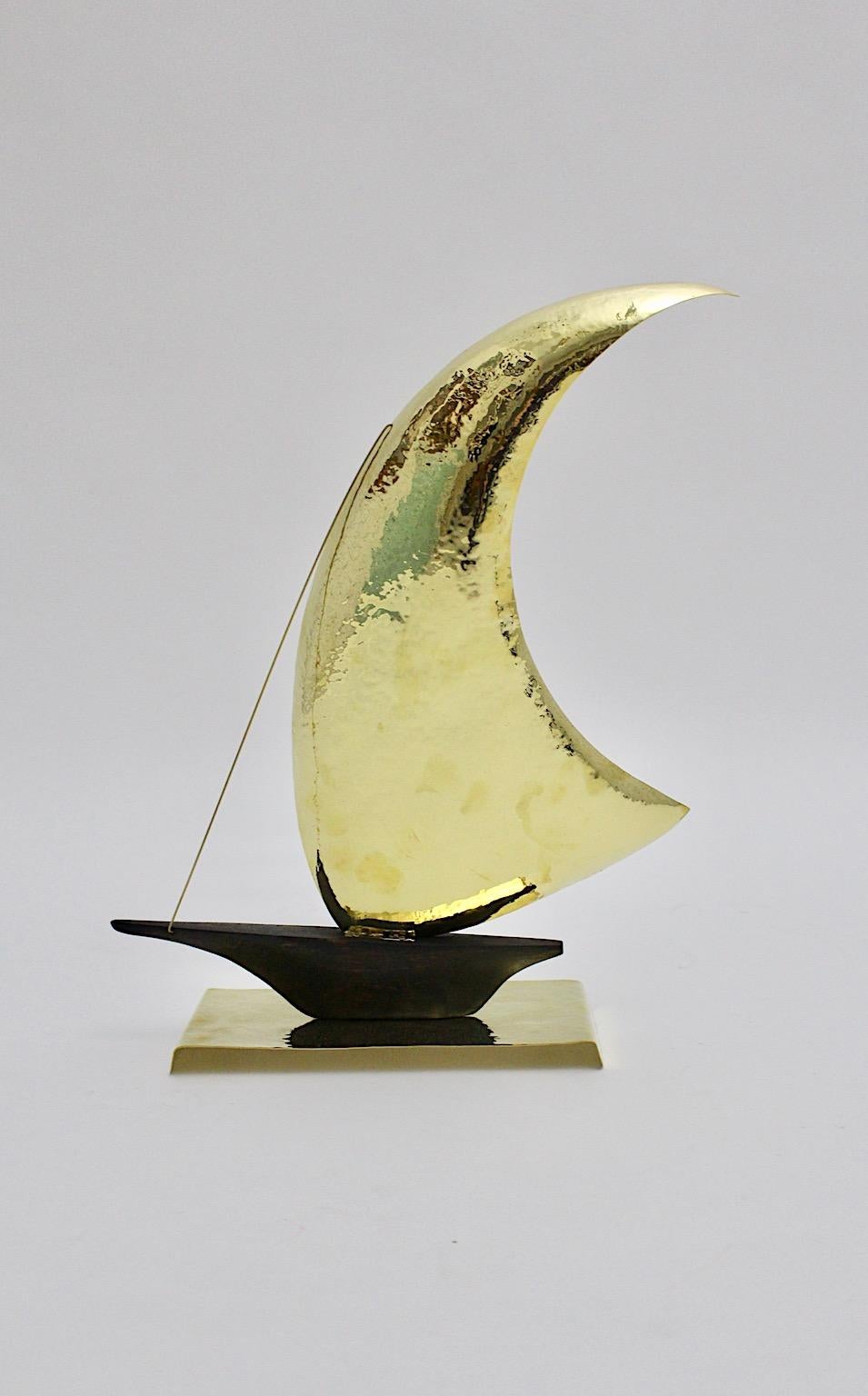 Mid Century Modern vintage sailing ship from hammered brass and oakwood designed and executed in Vienna 1950 in the style of Franz Hagenauer.
This amazing sailing ship from stained oakwood with a brass hammered sail and base is a beautiful work from
