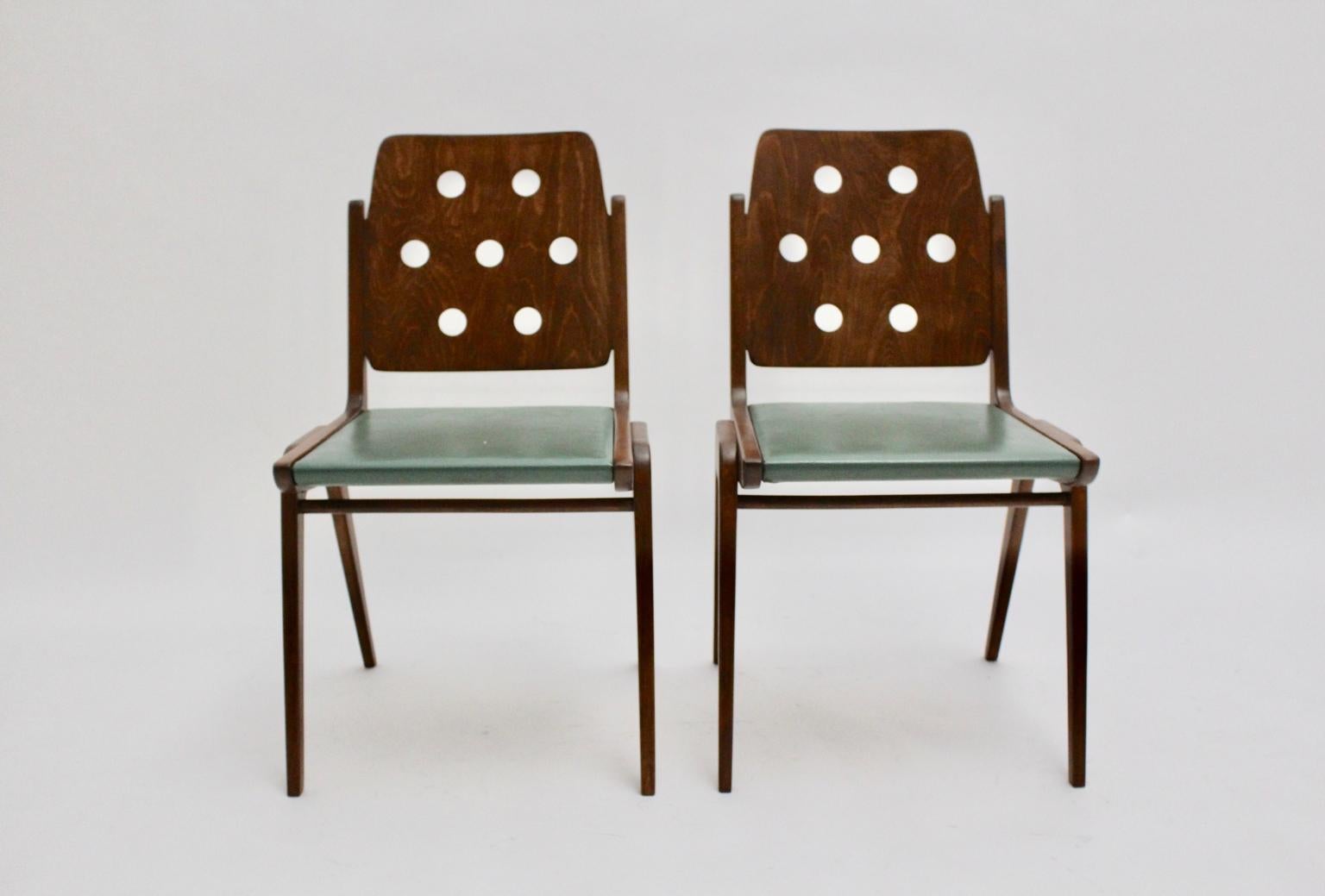 This pair of Franz Schuster dining chairs, Vienna 1950s, were made of solid beechwood and plywood. Also the seat is covered with the original green faux leather.
Furthermore the base and the perforated back with the significant seven holes were
