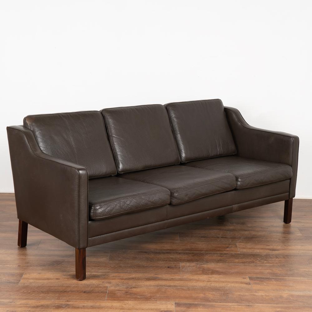 Mid-Century Modern vintage three seat leather sofa by Mogens Hansen, model MH195/3.
Upholstered in dark brown textured leather, loose cushions with zippers and fabric backs.
Hardwood legs in stained beechwood. 
Sold in used vintage condition,