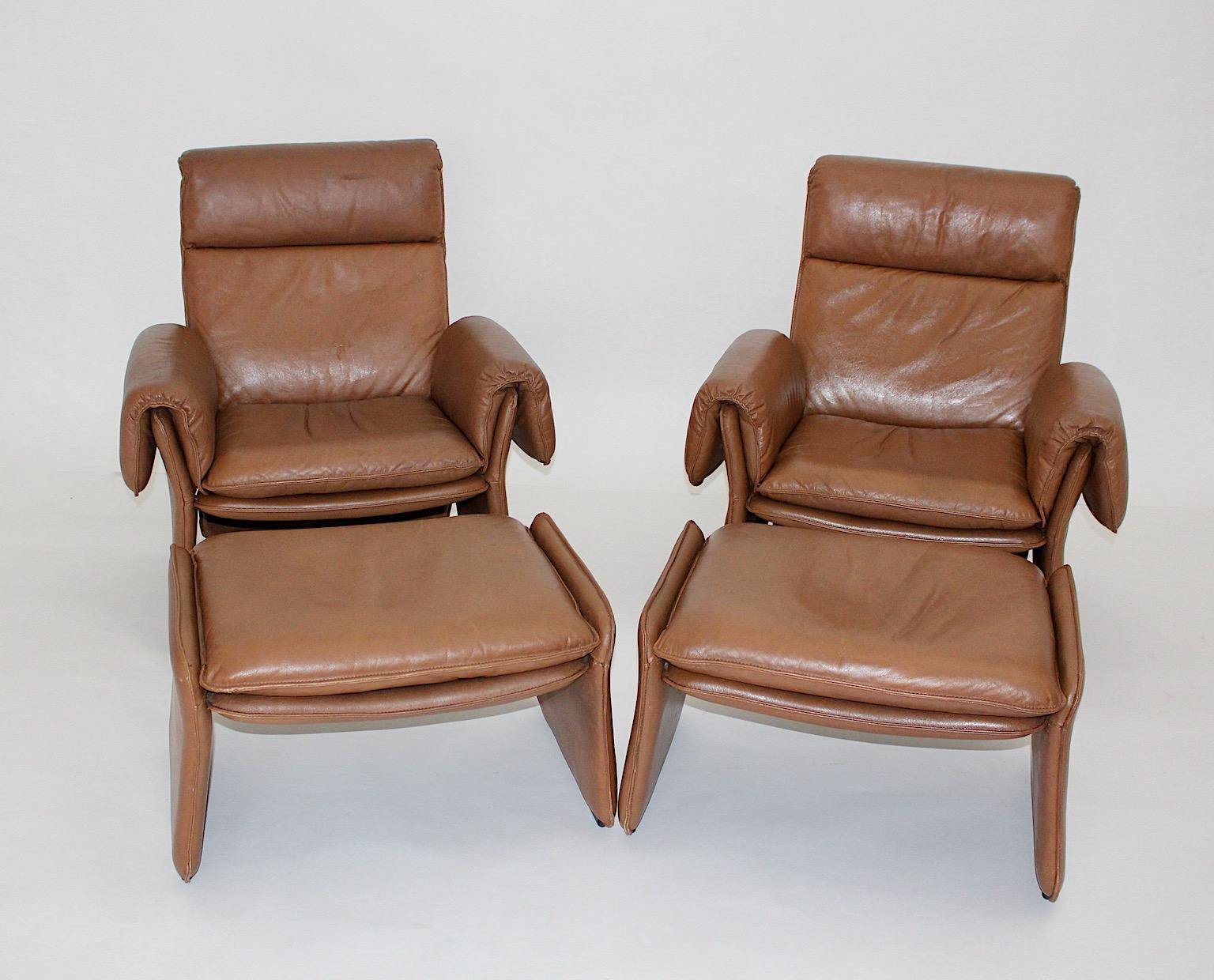 Mid-Century Modern vintage pair of lounge chairs or armchairs with ottoman from patinated treated leather in a warm caramel brown color tone.
The lounge chairs look similar to de Sede and were designed and manufactured 1960s Italy.
The surface is