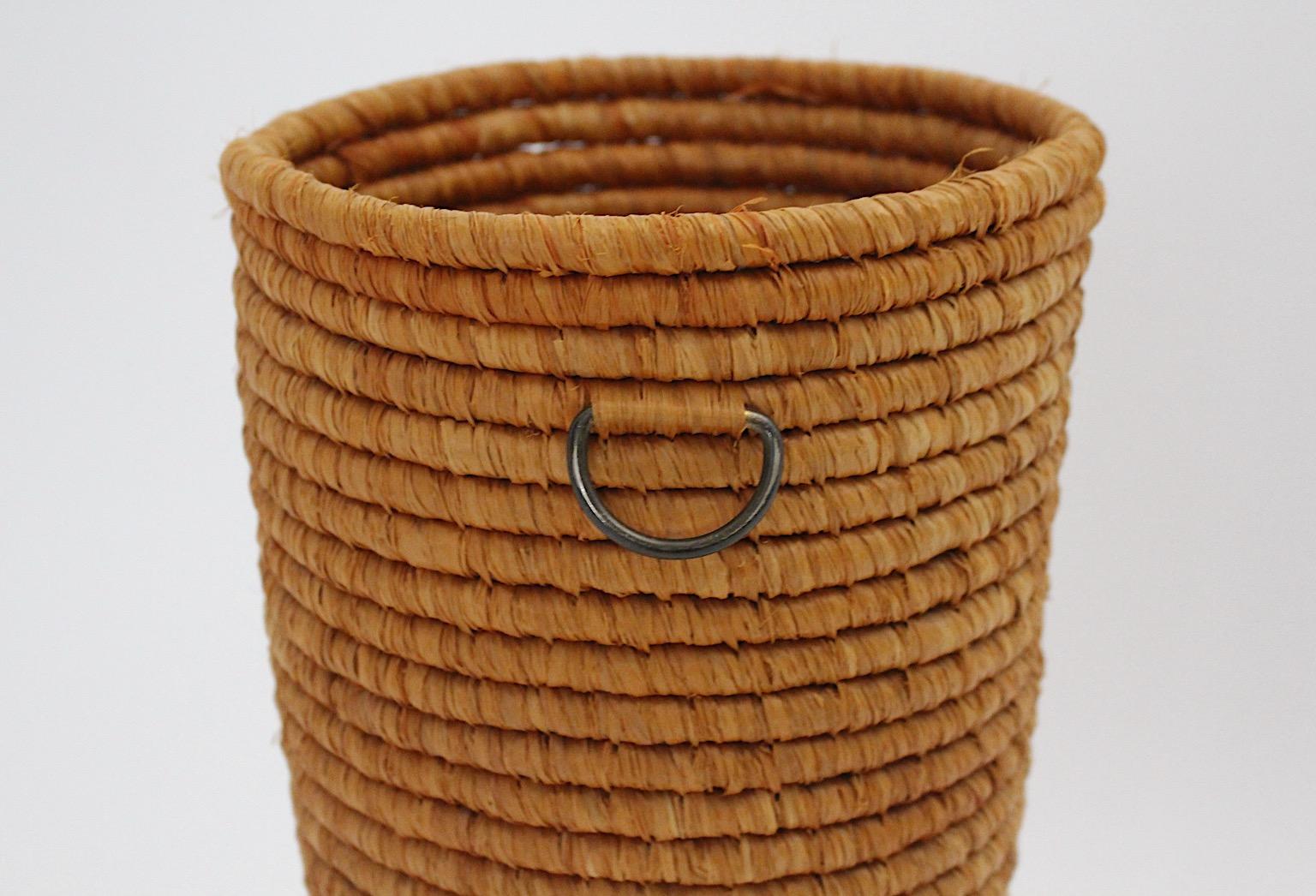 Mid-Century Modern vintage brown raffia and brass paper basket, or basket, which was designed and hand made, 1950s, Vienna, Austria.
The natural raffia network in a warm earthen tone and 2 brass handles on each side underlines the rustic look.
The