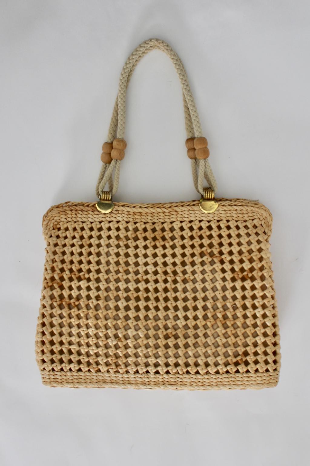 We present a charming Vintage Straw Shoulder Bag with decorating wooden balls and brass details.
The straw bag features cords to carry the bag over the shoulder or as handle bag furthermore the bag features an off white canvas inlay with one side