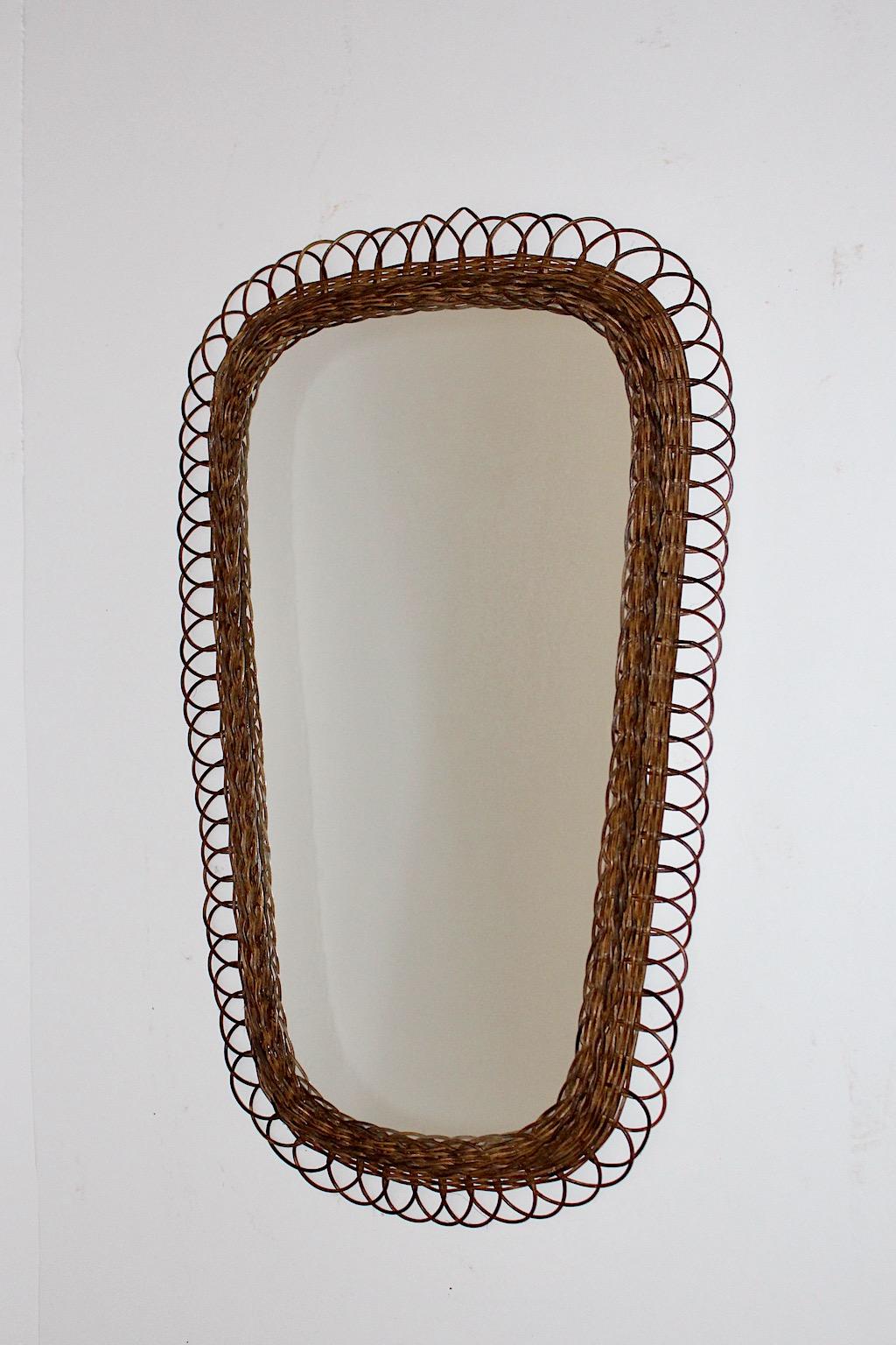 Mid Century Modern vintage wall mirror oval like framed with willow loops and mirror glass Germany 1960s.
While the dark brown willow work frame is in good condition without damages, the mirror glass shows cloudy mirror patina.
Good condition with