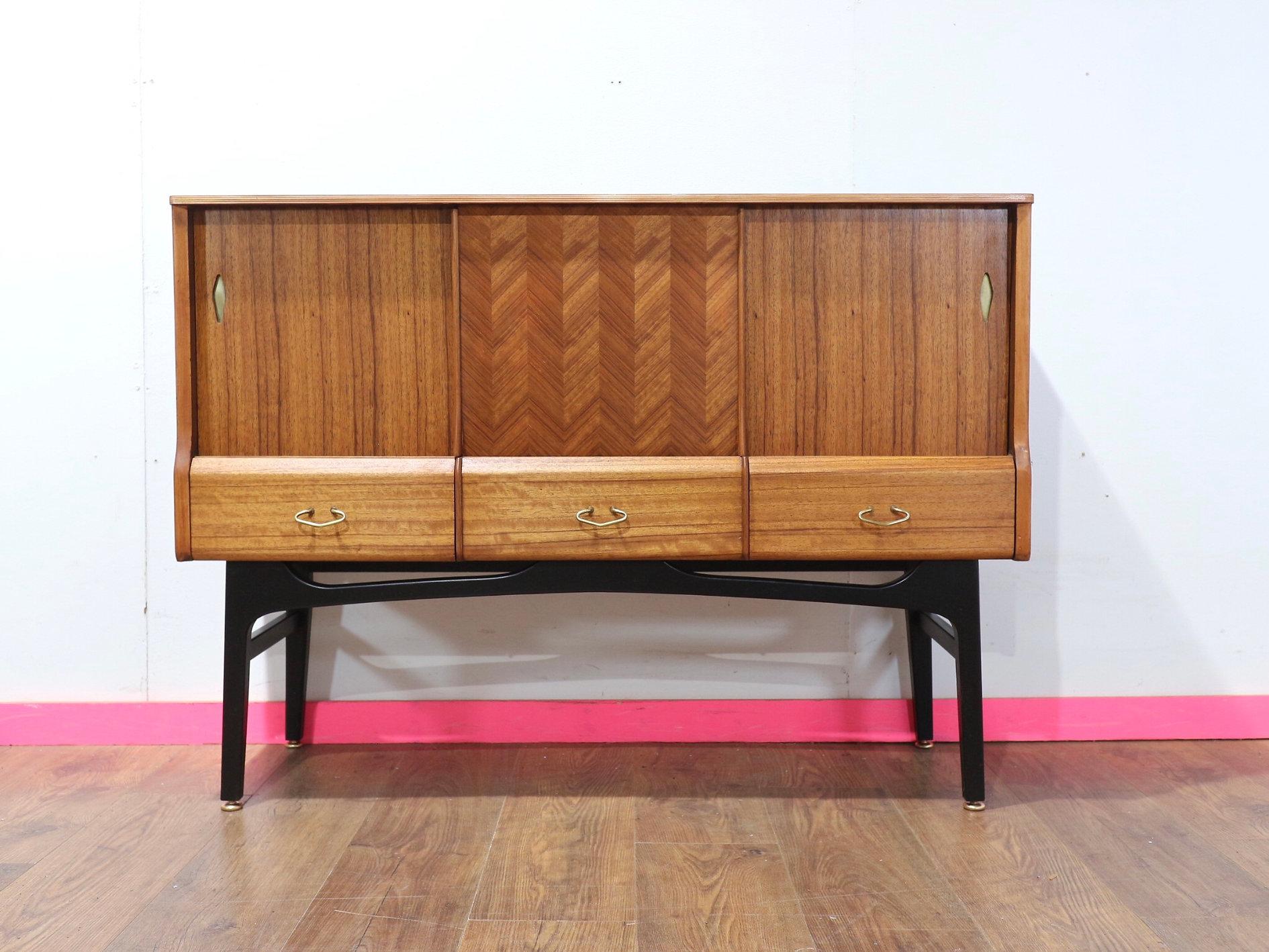 Discover the elegance of mid-century modern design with this stunning buffet sideboard by British furniture maker Jentique. Featuring gorgeous legs this compact credenza combines form and function seamlessly. The sliding door showcases a beautiful