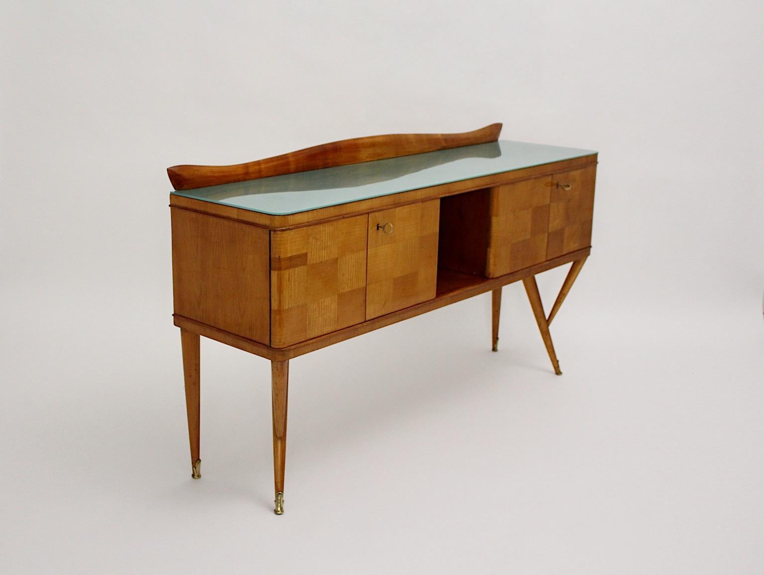Mid Century Modern vintage sideboard Ico Parisi style from solid cherrywood topped with green turquoise teal glass plate and beautiful brass details designed and manufactured Italy 1940s.
This cherrywood shows warmth and depth with a chess like