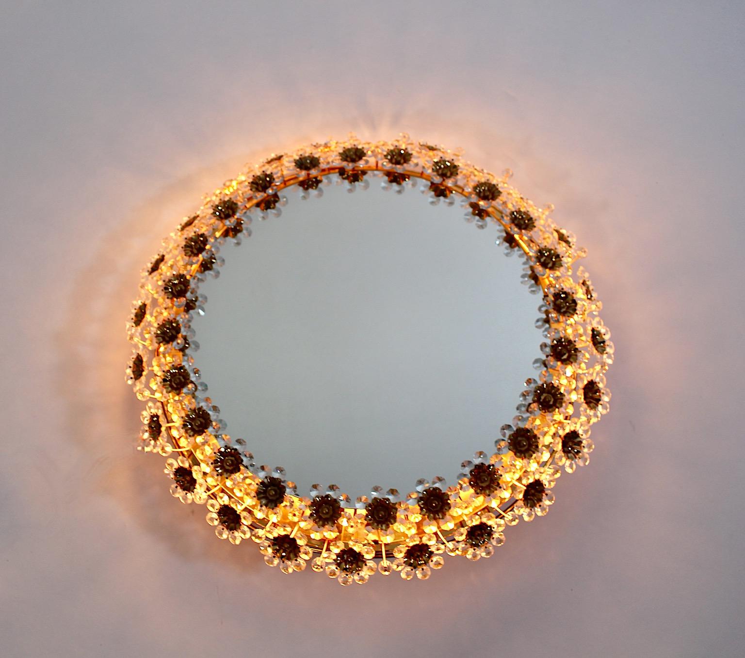 Mid Century Modern vintage circular wall mirror with backlight from gilt brass and crystal flowers in earthen soft brown, gold and clear colors 1960s, Germany.
A stunning delicate wall mirror in circular shape shows a frame decor with clear crystals