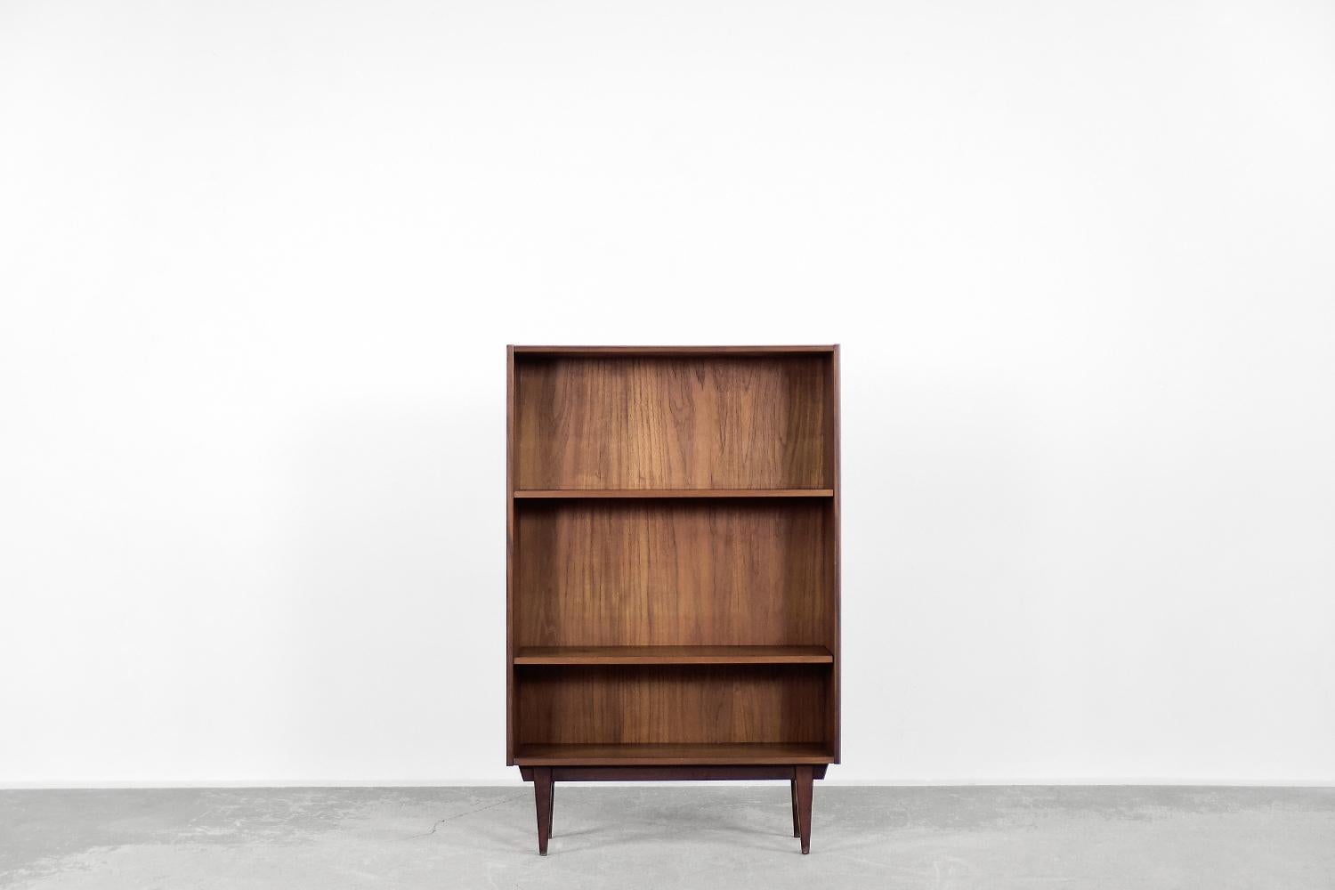 This modernist classic bookcase was made in Sweden during the 1960s. It is finished with teak wood in a darker shade of brown. The cabinet has three shelves, and the height of two of them is adjustable. The piece of furniture is mounted on solid