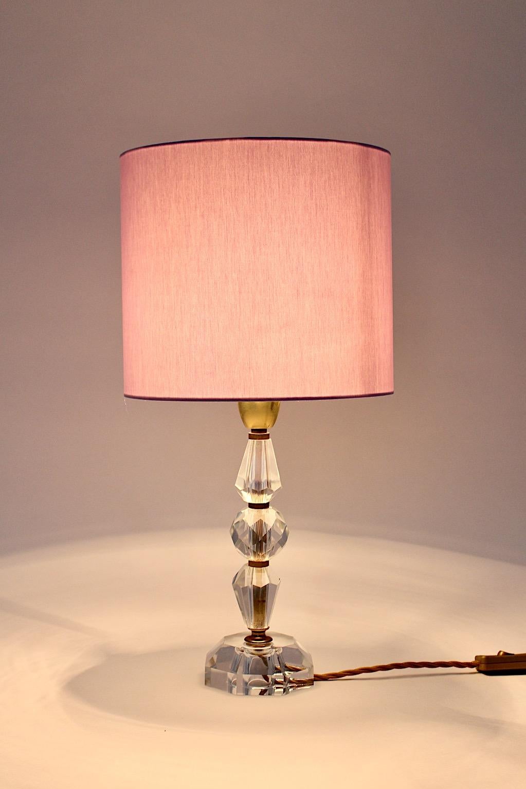 Mid Century Modern vintage table lamp from polished clear crystal glass and soft lavender lamp shade from textile fabric by Bakalowits 1950s Vienna.
While the base is build of brass details and polished crystal glass elements in different geometric