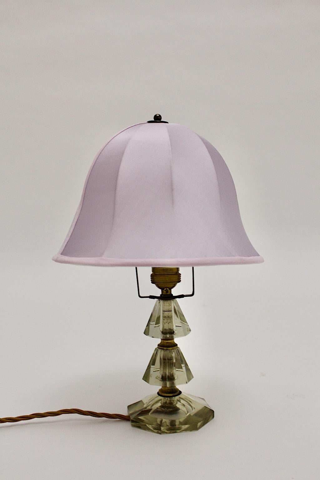 Mid Century Modern Vintage Tischlampe aus geschliffenem Glas und Messing von Bakalowits & Söhne 1950s Wien.
Während der Sockel der Tischleuchte geometrische Elemente aus geschliffenem Klarglas zeigt, ist der glockenförmige Lampenschirm in