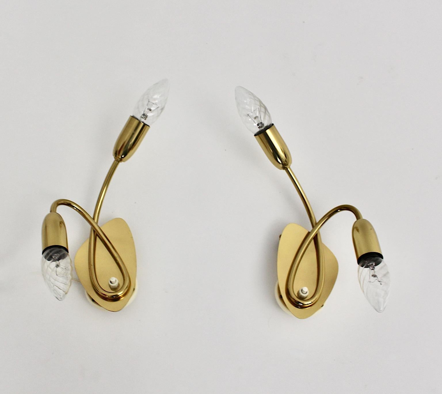 Mid Century Modern vintage pair of sconces or wall lights from brass in elegant curved shape 1950s Italy.
A graceful pair of wall lights or sconces from brass each with two E 14 sockets and a push button at the base.
This duo of wall lightings