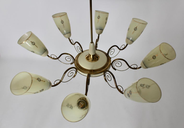 This handmade eight arms Mid-Century Modern vintage Italian chandelier was made of brass, brassed details, brass ivory lacquered and glass.
The curved eight arms were made of brass tubes and the beautiful ivory glass shades were decorated and hand