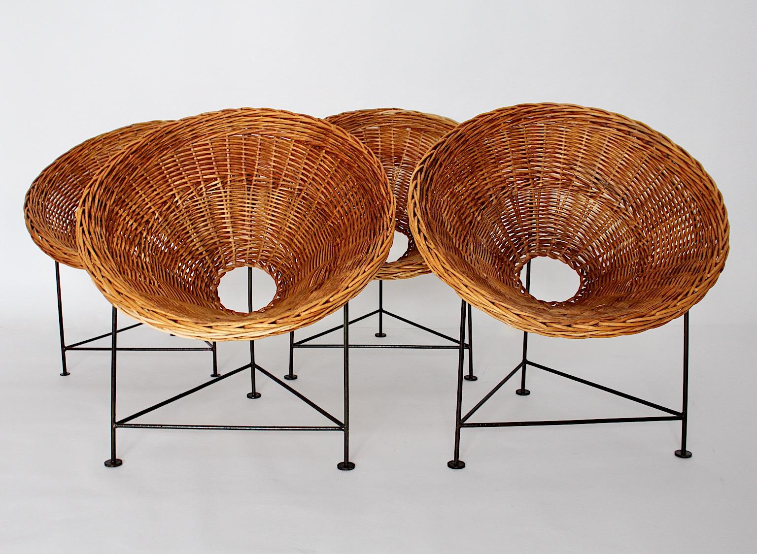 Mid-Century Modern Vintage Satz von vier Lounge-Stühle oder Terrassenstühle aus Weide Netzwerk und schwarz lackiertem Metallrahmen.
Der schöne Eimer- oder Kegelsitz aus Weidengeflecht in einem honigbraunen Ton, dem Sie helle Farbtöne für ein