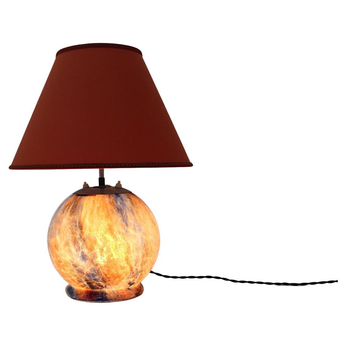 Mid-Century Modern vintage table lamp with glass base ball like and a triangle shape lamp shade in textile fabric 1940s Germany.
The beautiful glass ball with many colors like burnt orange, red, brown and blue is very similar to the glass marbles