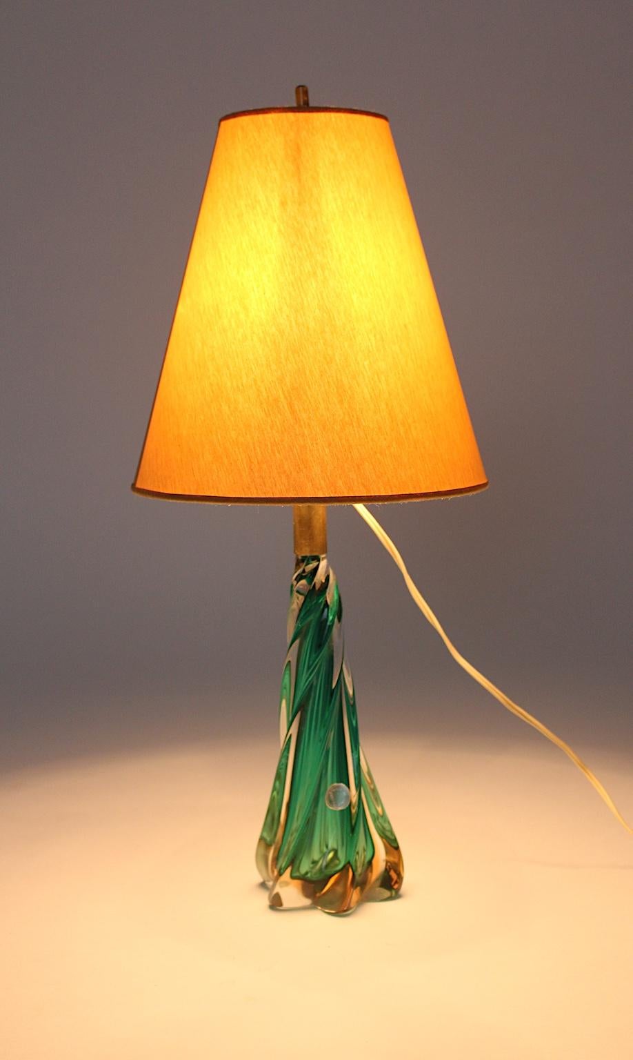 Moderne Tischlampe aus Glas aus der Jahrhundertmitte, entworfen und hergestellt in Murano, Venedig, Italien, 1950er Jahre.
Der schöne gedrehte grüne Tischsockel wurde aus mundgeblasenem Glas mit goldenen Einsprengseln hergestellt und weist auch