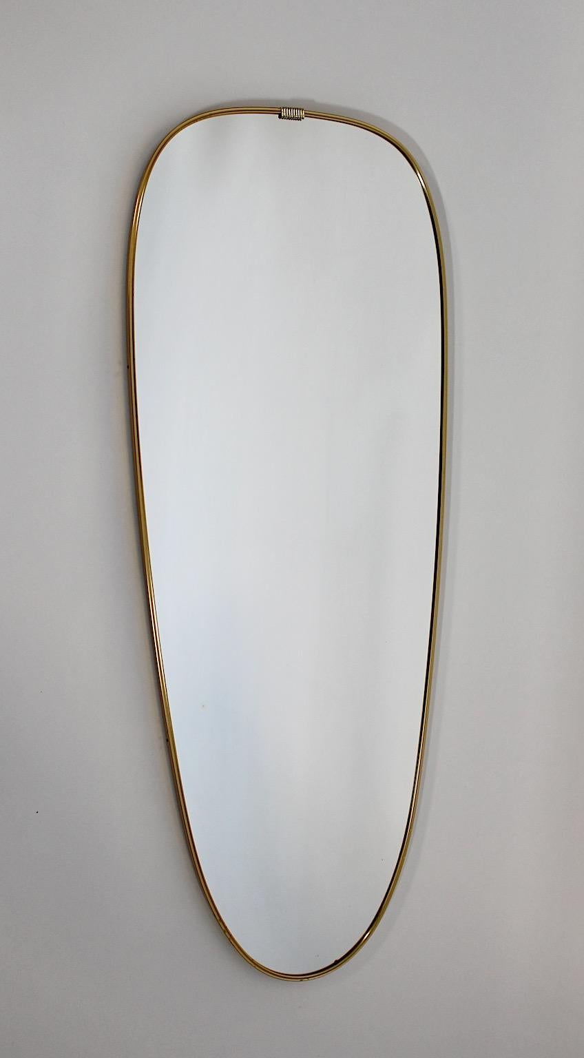 Mid Century Modern vintage full length mirror wall mirror from brass and golden metal 1950s.
An elegant full length mirror or floor mirror in simple but sophisticated conical shape with golden brass frame and a small detail at the top.
Backside one