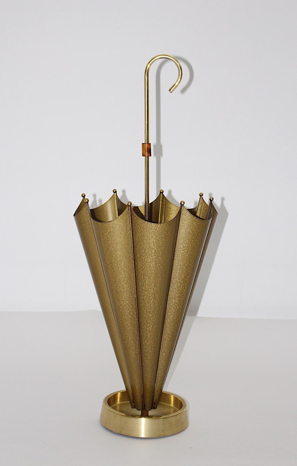 Mid-Century Modern vintage umbrella stand from metal and brass in gold metallic color tone 1950s Italy.
The stunning umbrella stand shows a brass drip cup, brass balls and an umbrella like stand from golden metal.
The handle features a bamboo