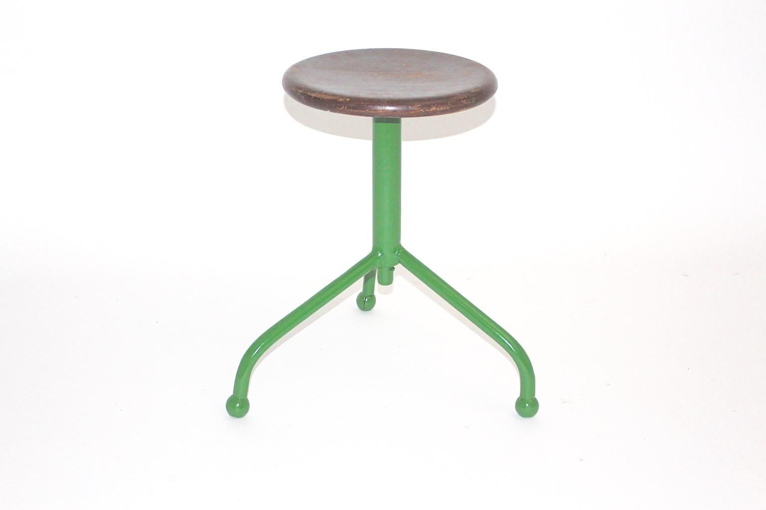 This Mid-Century Modern vintage green metal and wood industry stool 1950s features three legs and a wooden seat with brown painted color rests.
Also at the end of the newly green lacquered metal feet wooden balls are fixed.
The vintage condition