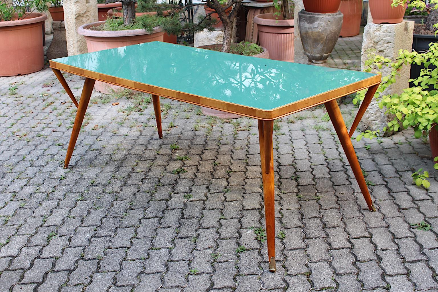 Mid Century Modern vintage dining table or writing desk or bureau plat very similar to Ico Parisi from solid cherrywood topped with green turquoise teal glass plate and beautiful brass details designed and manufactured Italy 1940s.
The cherrywood
